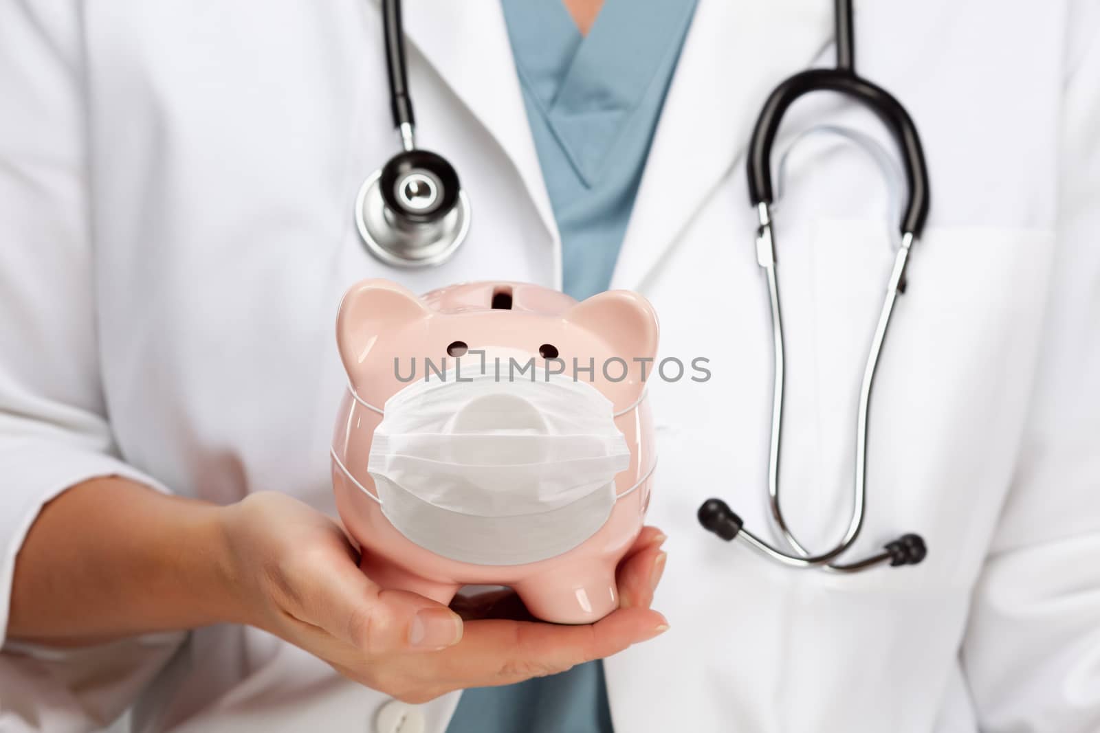 Doctor with Stethoscope Holding Piggy Bank Wearing Medical Face Mask.