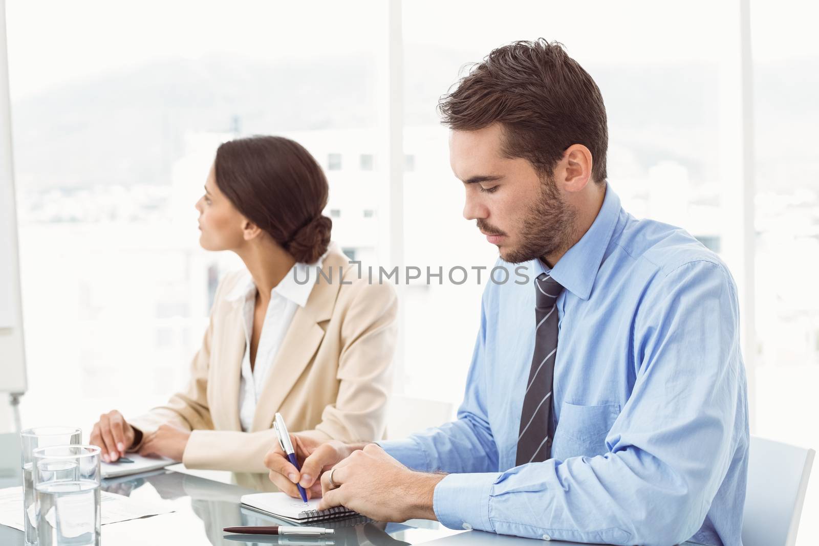 Two young business people in board room meeting at office