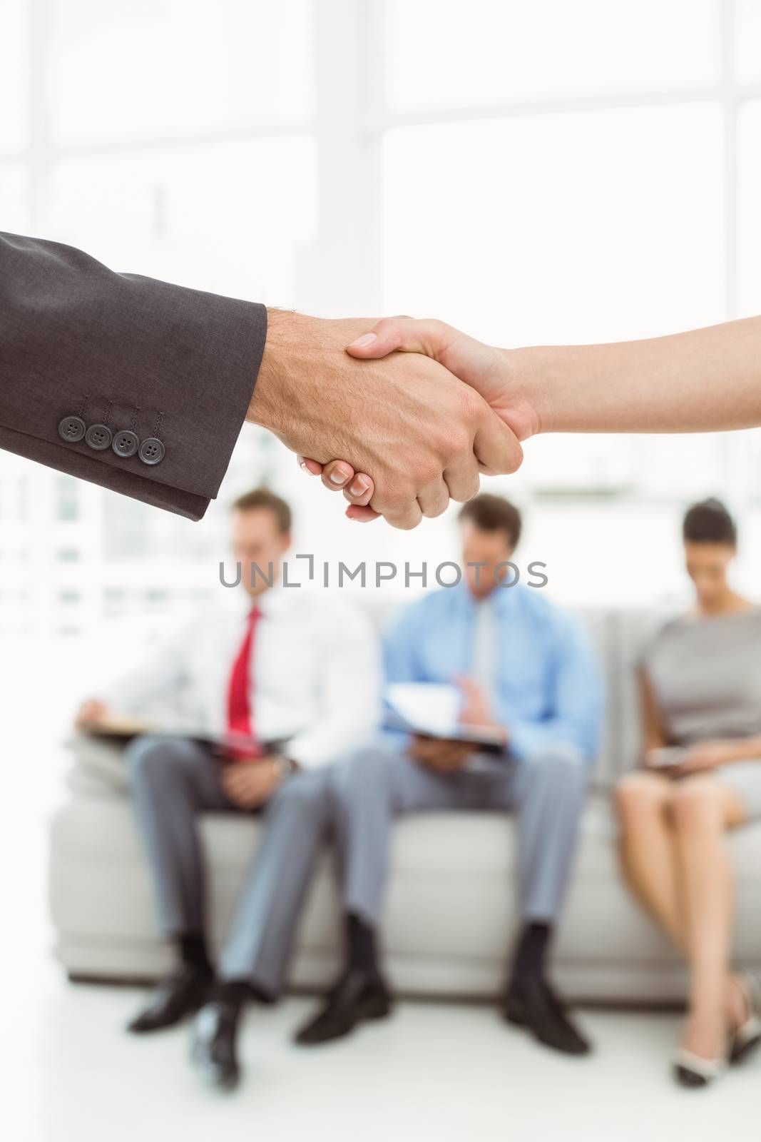 Handshake besides people waiting for job interview in office