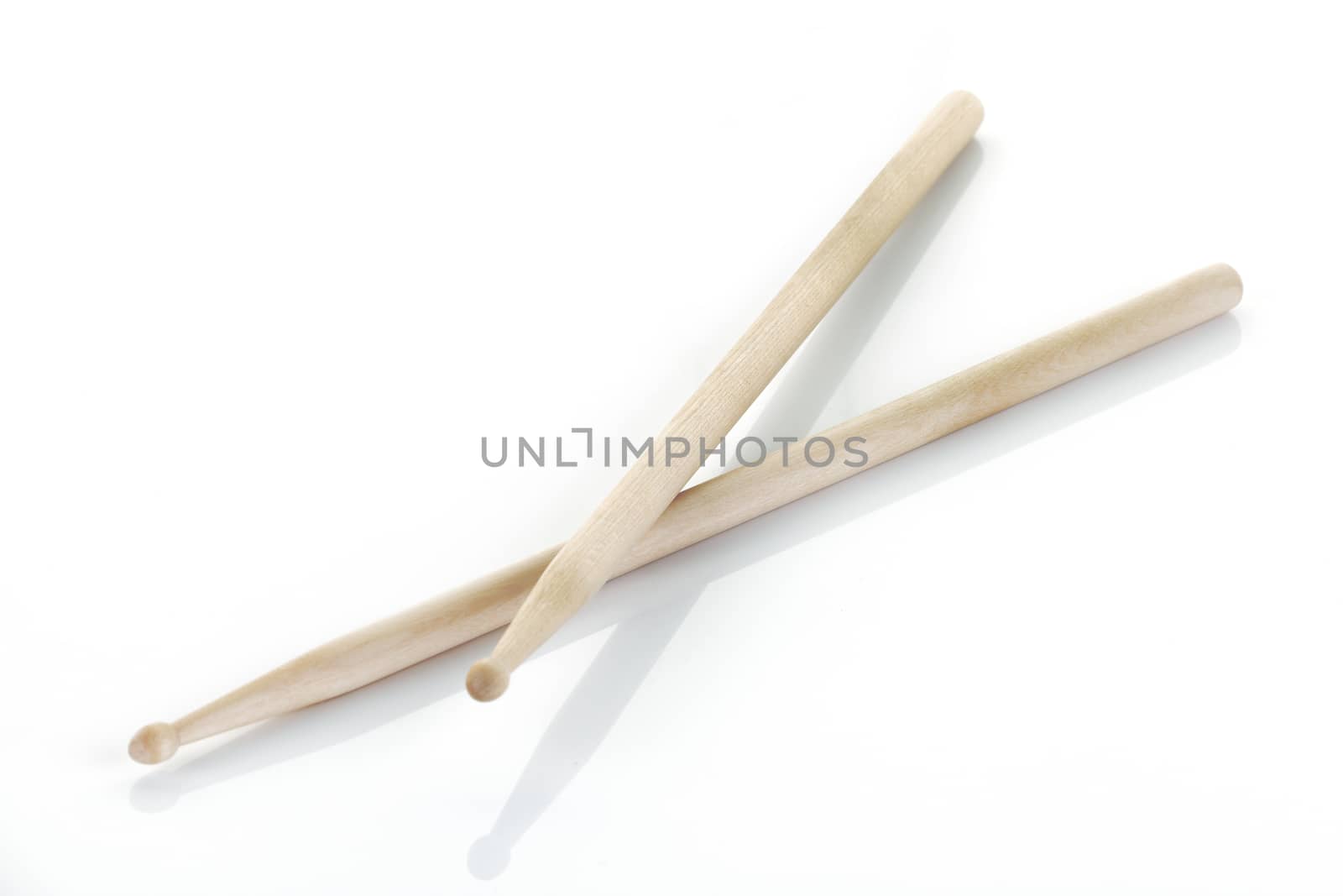 A pair of drumsticks on white surface with shadow