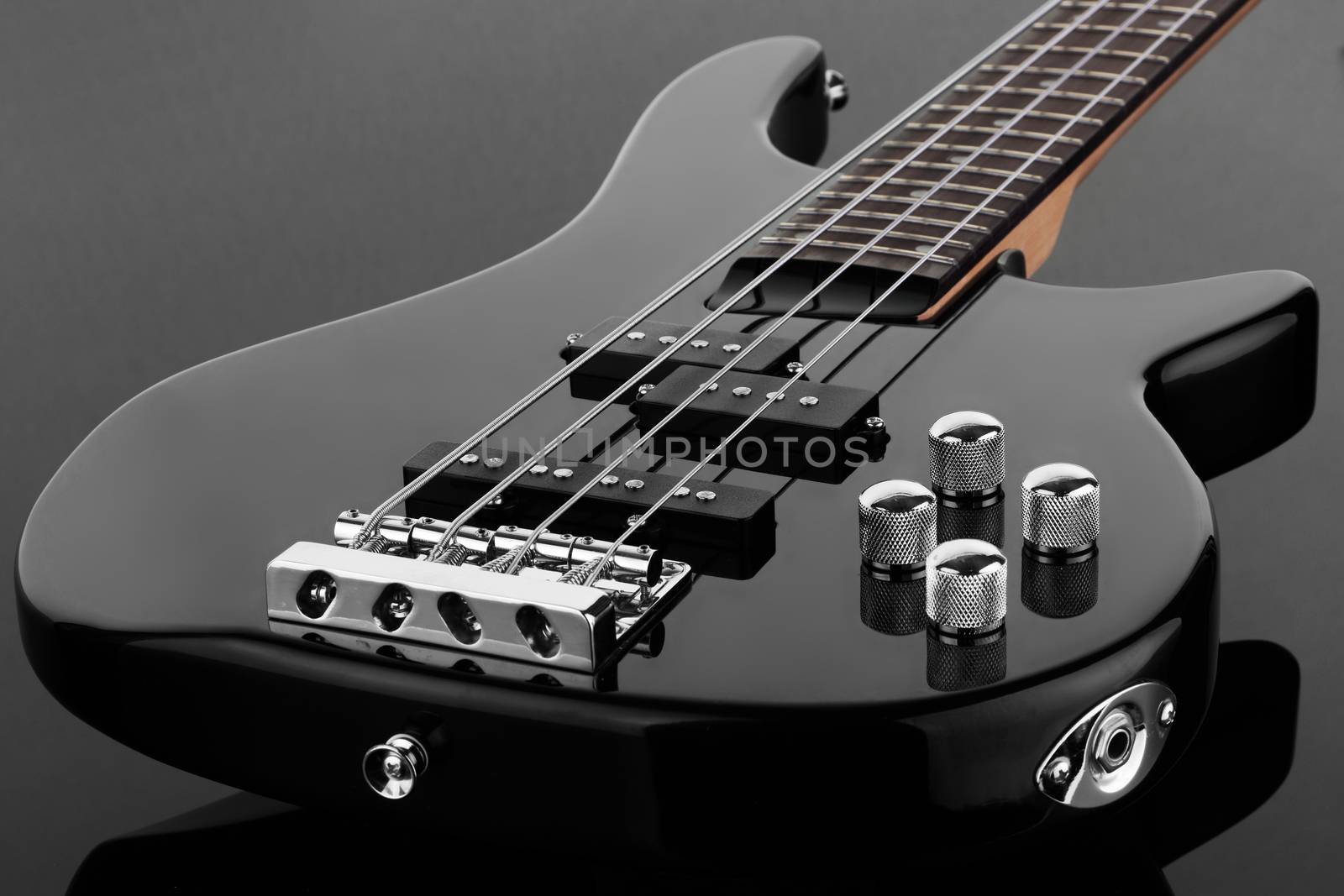The body of black electric bass guitar on dark background