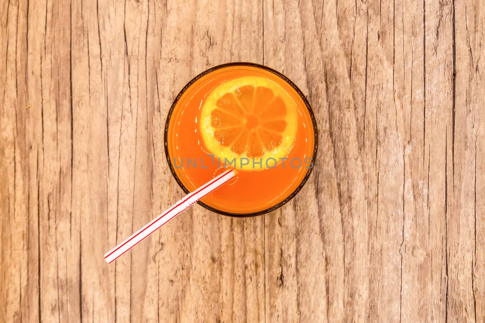 Multifruit juice in a glass with a straw viewed from above on a wooden background