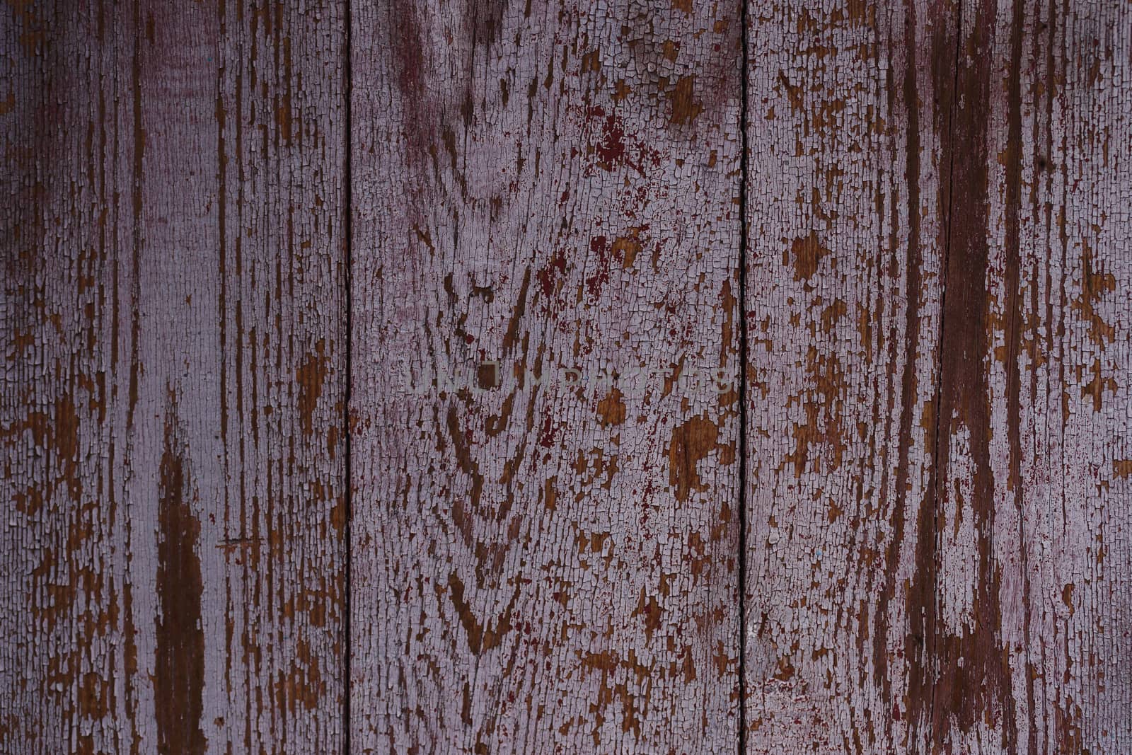 Old red wooden texured door surface closeup. Relief on surface. Stock photo of old wooden door pattern of aged boards with scratches. Red and gray colors on photo.