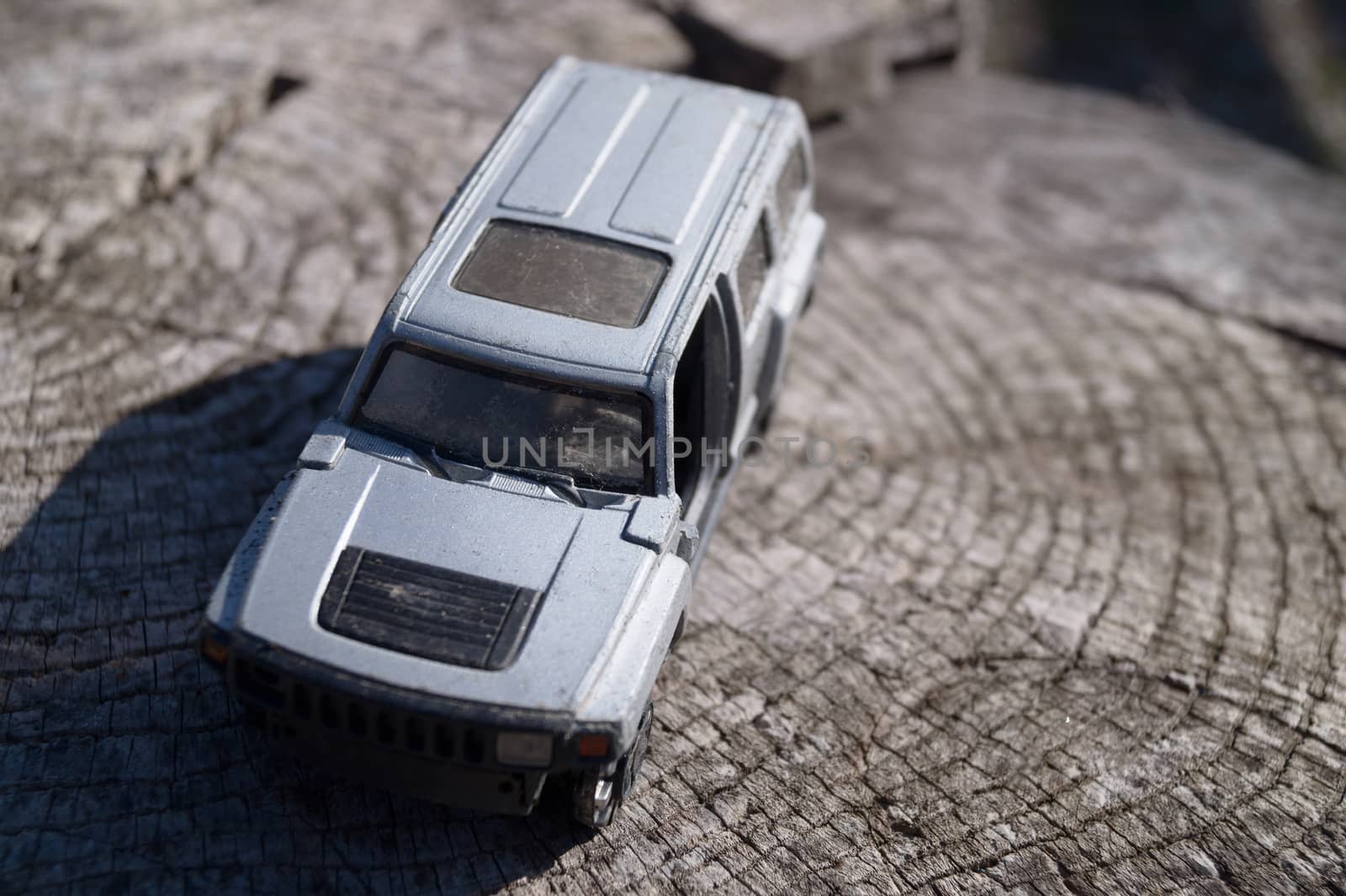 A silver toy car on wooden background. This is jeep offroad SUV made in metal