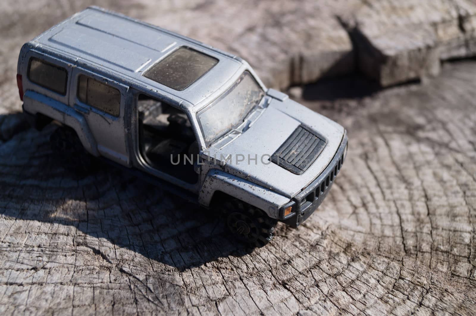 A silver toy car on wooden background. This is jeep offroad SUV made in metal by alexsdriver