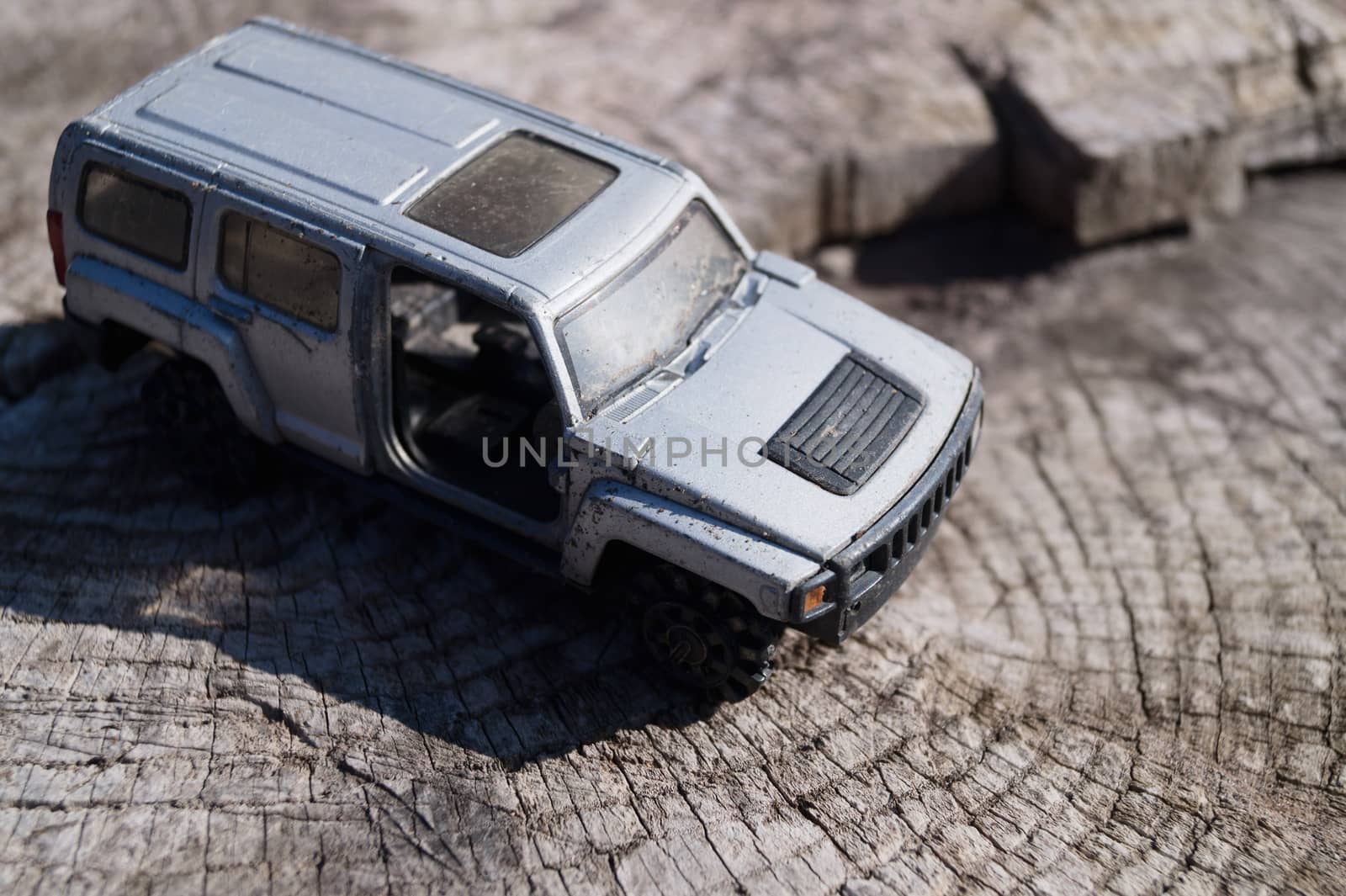 A silver toy car on wooden background. This is jeep offroad SUV made in metal