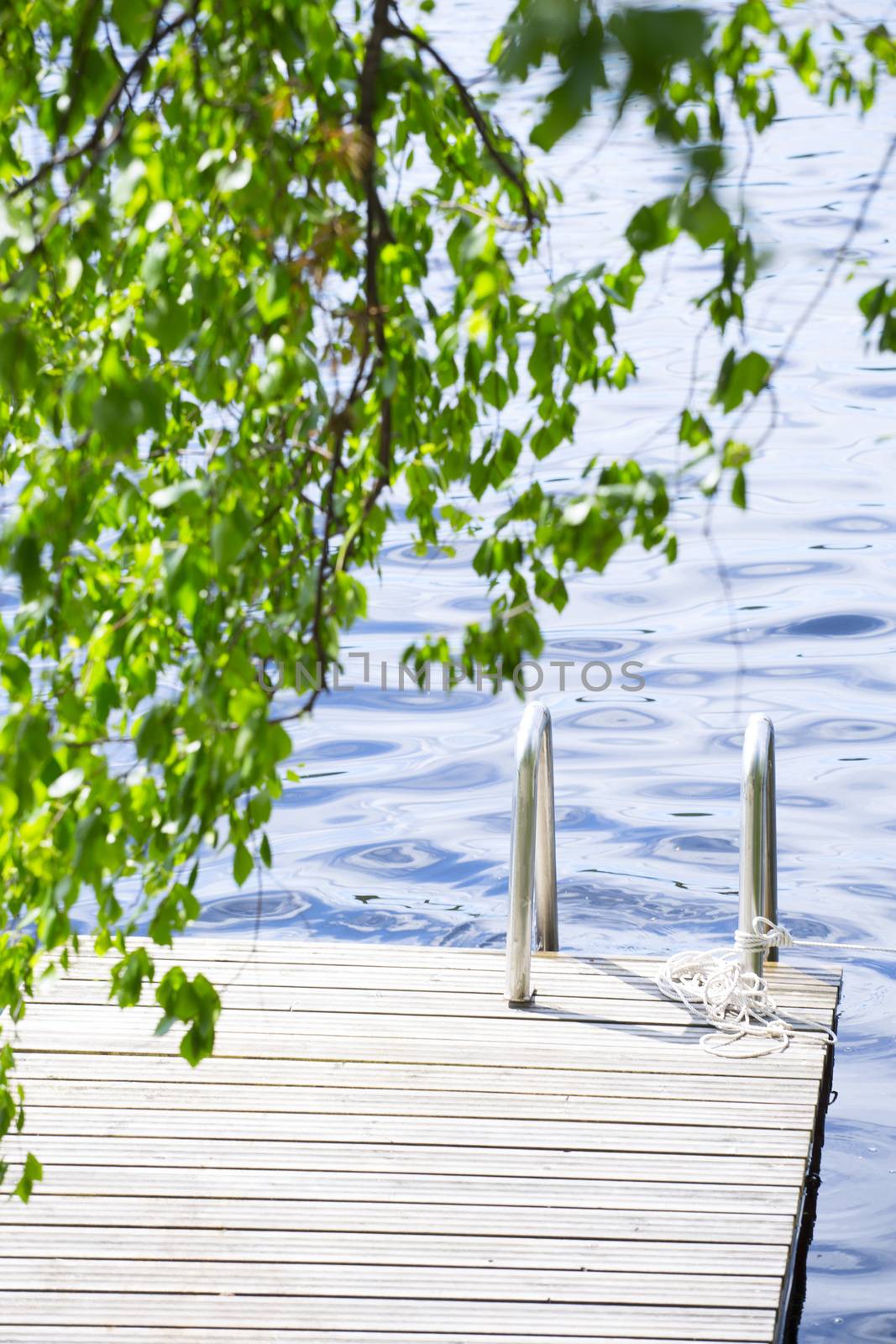 Wooden walkway jetty pier with railing for swimming in lake in Finland