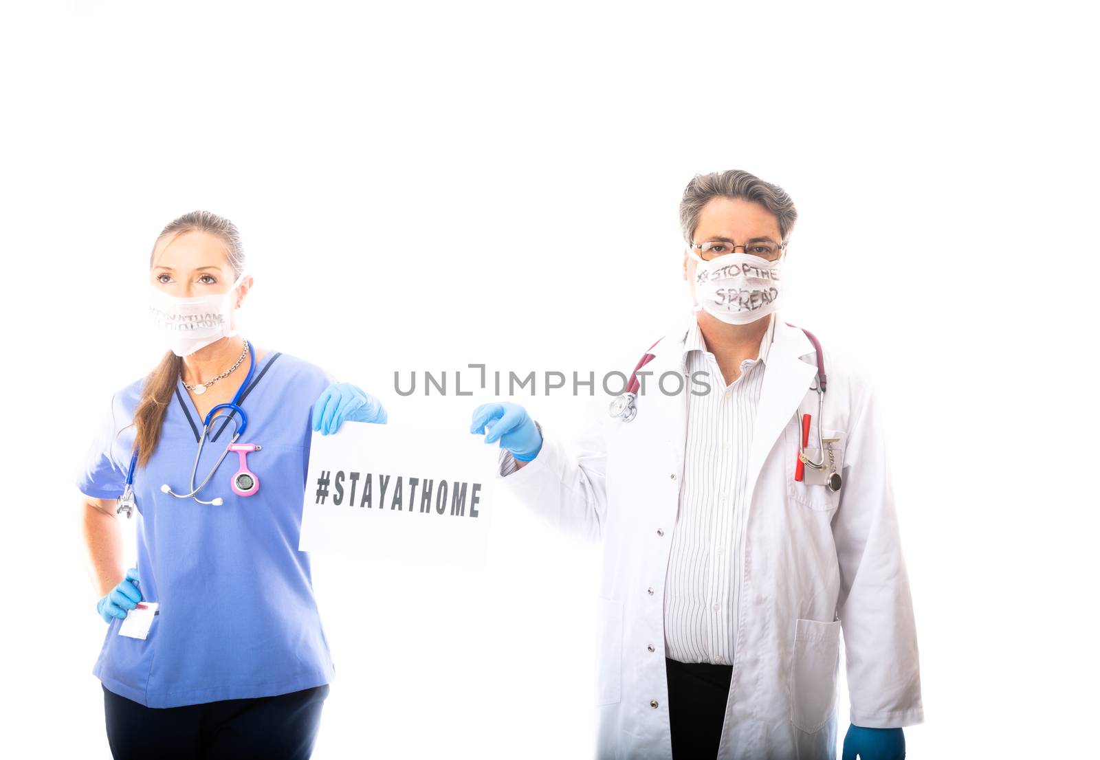 Two medical practitioners, hospital workers hold a sign to encourage strongly community to stay at home to stop the spread of a contagious disease pandemic