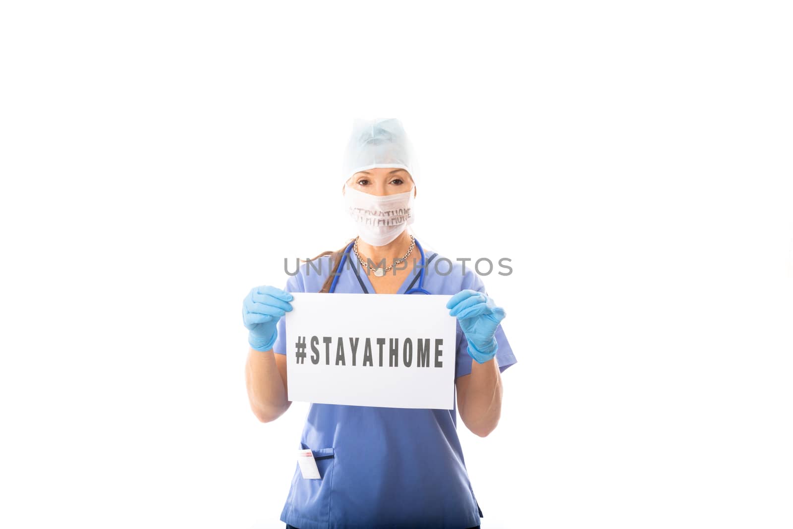 COVID-19 Doctor Nurse holding a sign encouraging community to stay at home during the COVID-19 virus pandemic.  She is wearing medical scrubs, gloves and mask with a message
