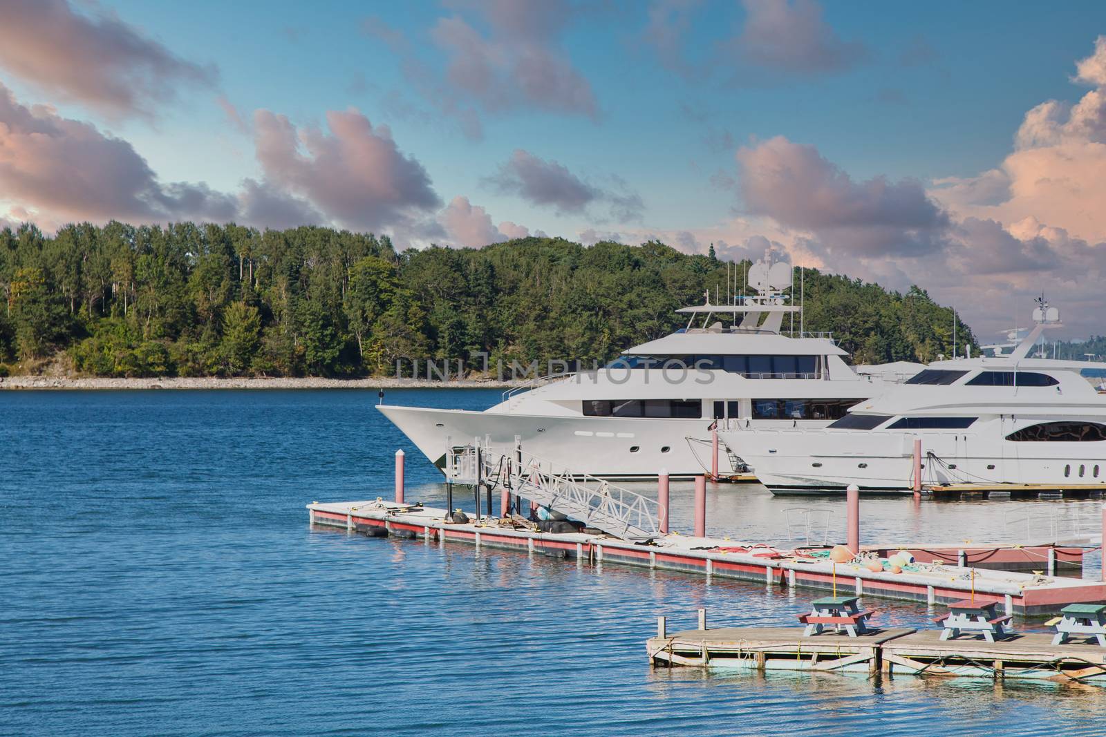 Two white luxury yachts at a pier in a harbor in Maine