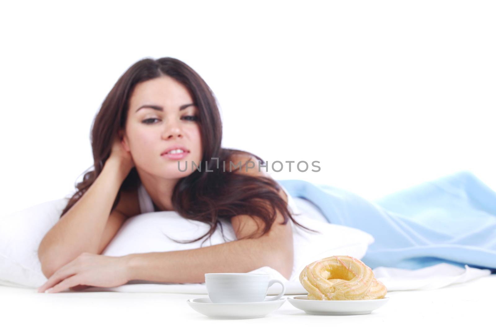 Woman eating a donut and drink coffee in the bed isolated on white background