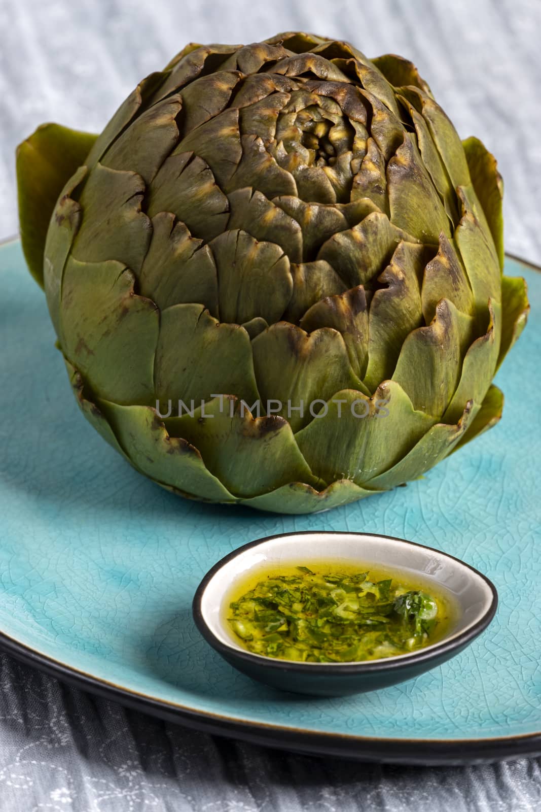 cooked artichoke on a blue plate by bernjuer