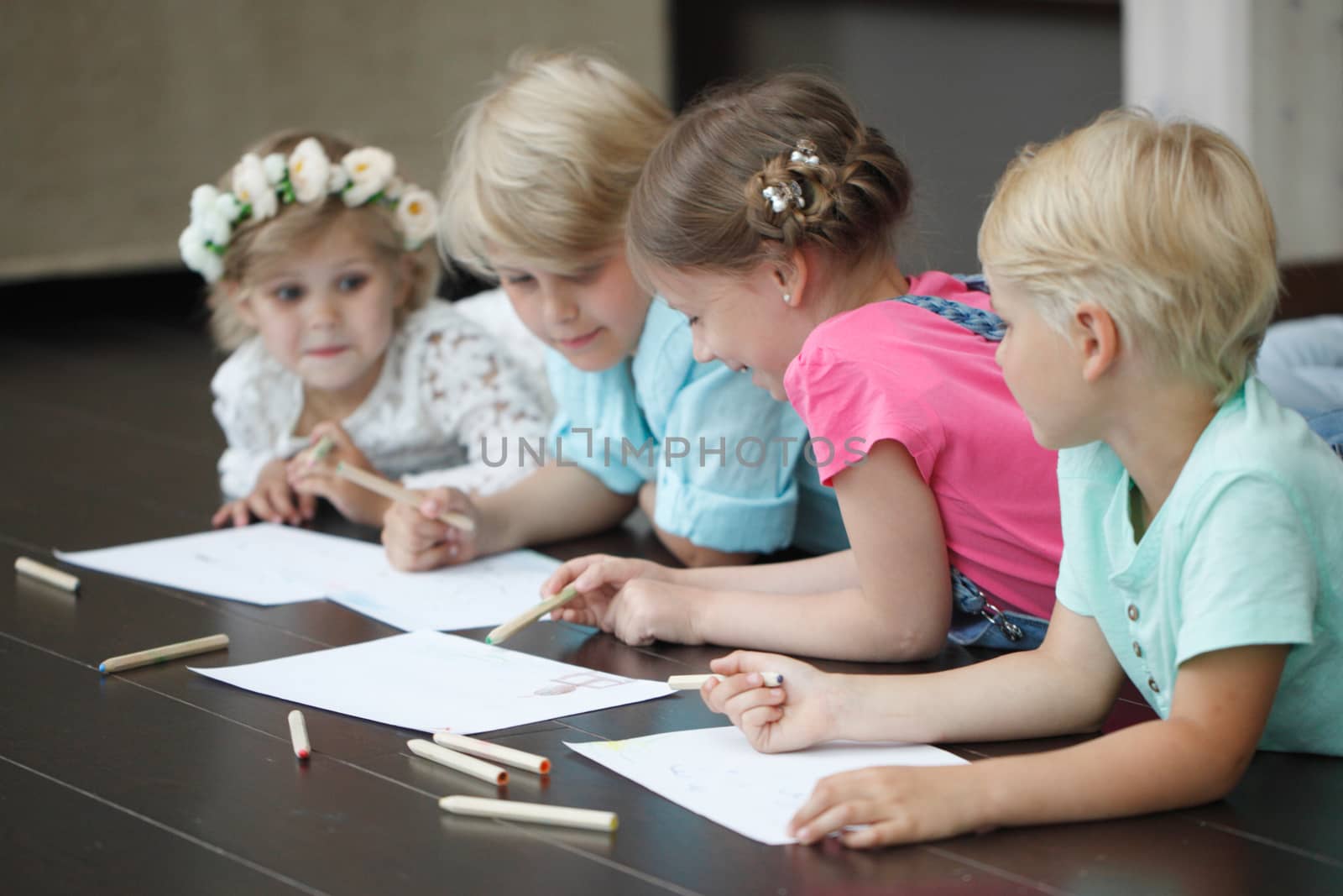 Cute little children friends drawing with pencils at home laying on floor