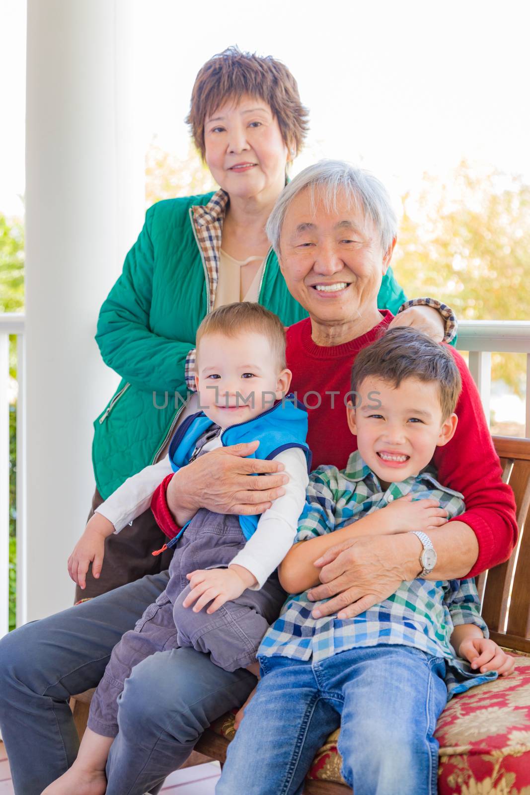Senior Adult Chinese Couple Sitting With Their Mixed Race Grandchildren by Feverpitched