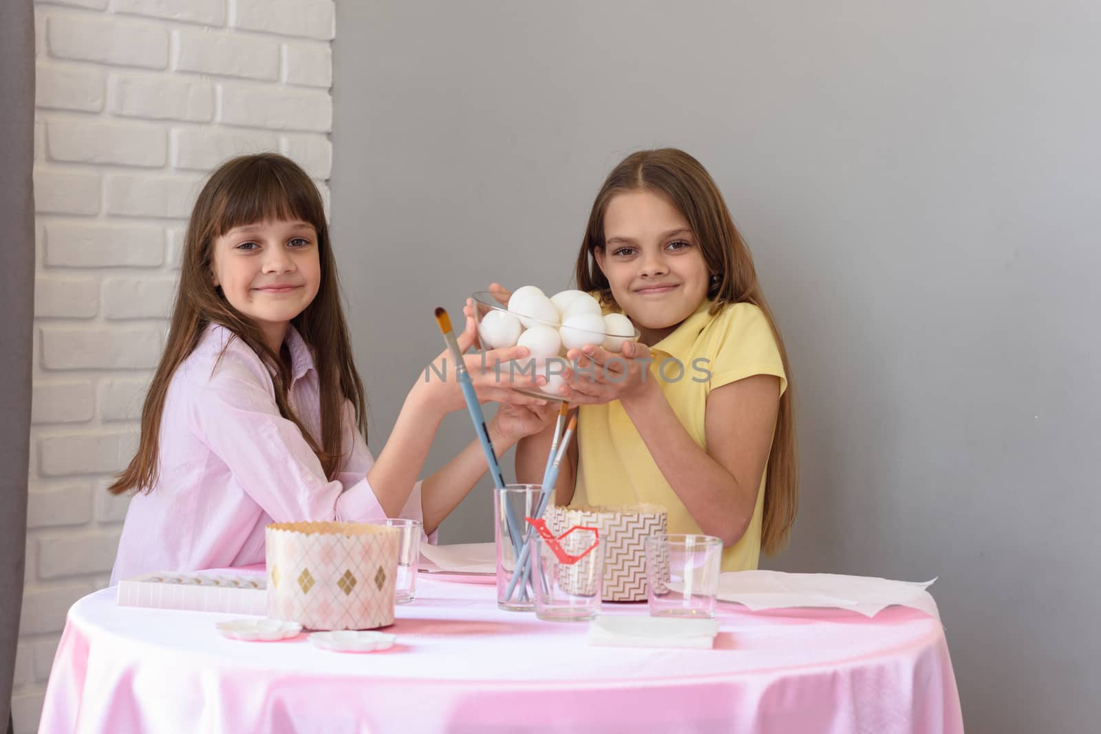 Children hold a large plate with chicken eggs before coloring for Easter