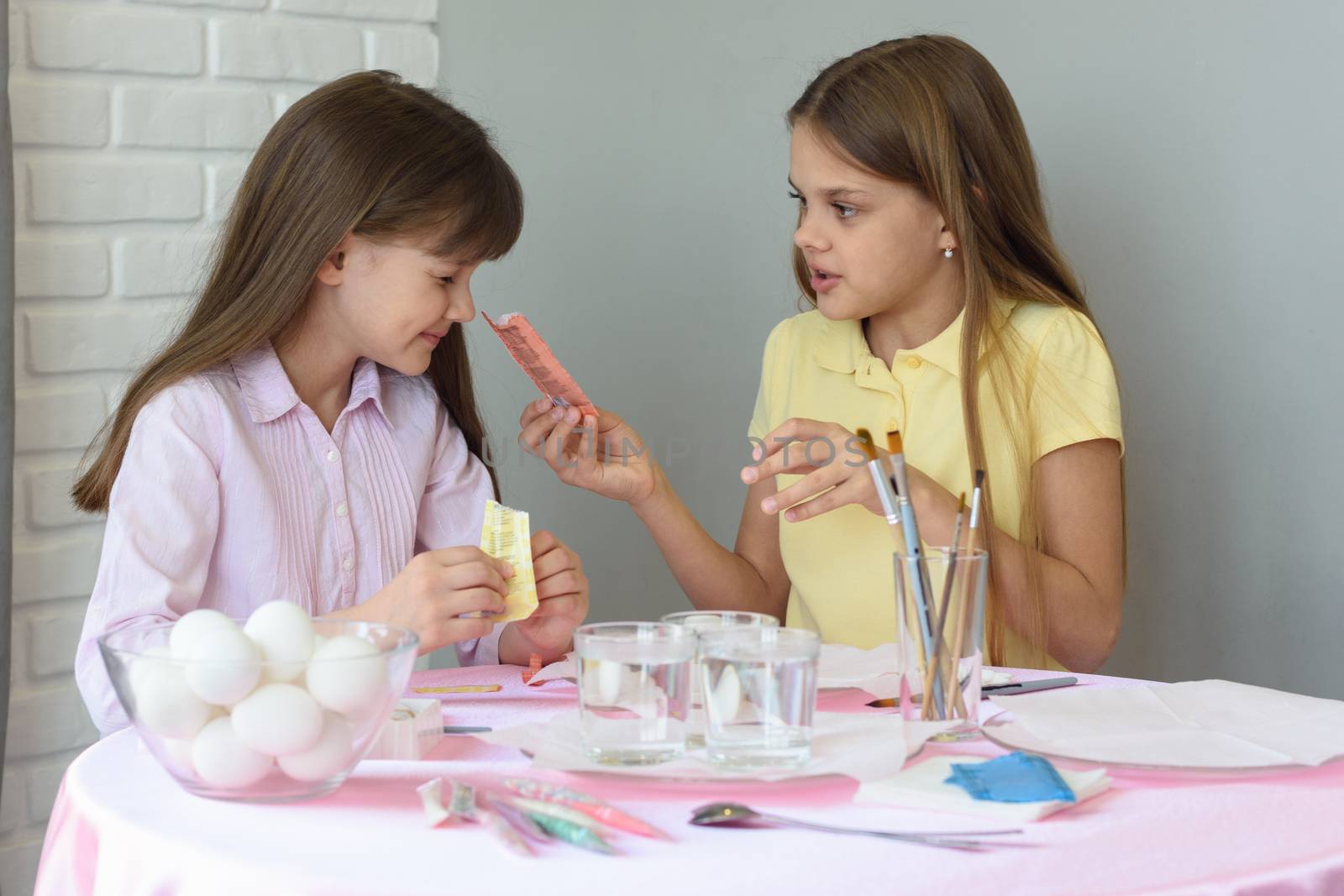 A girl shows the other girl the contents of a bag of food coloring