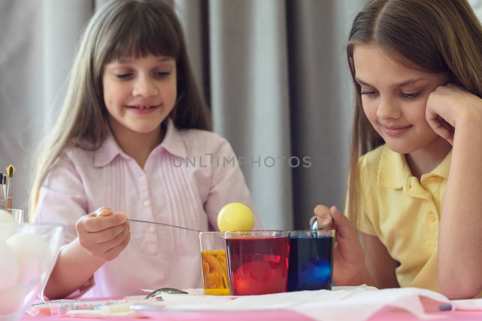 Children paint Easter eggs in glasses with liquid dye