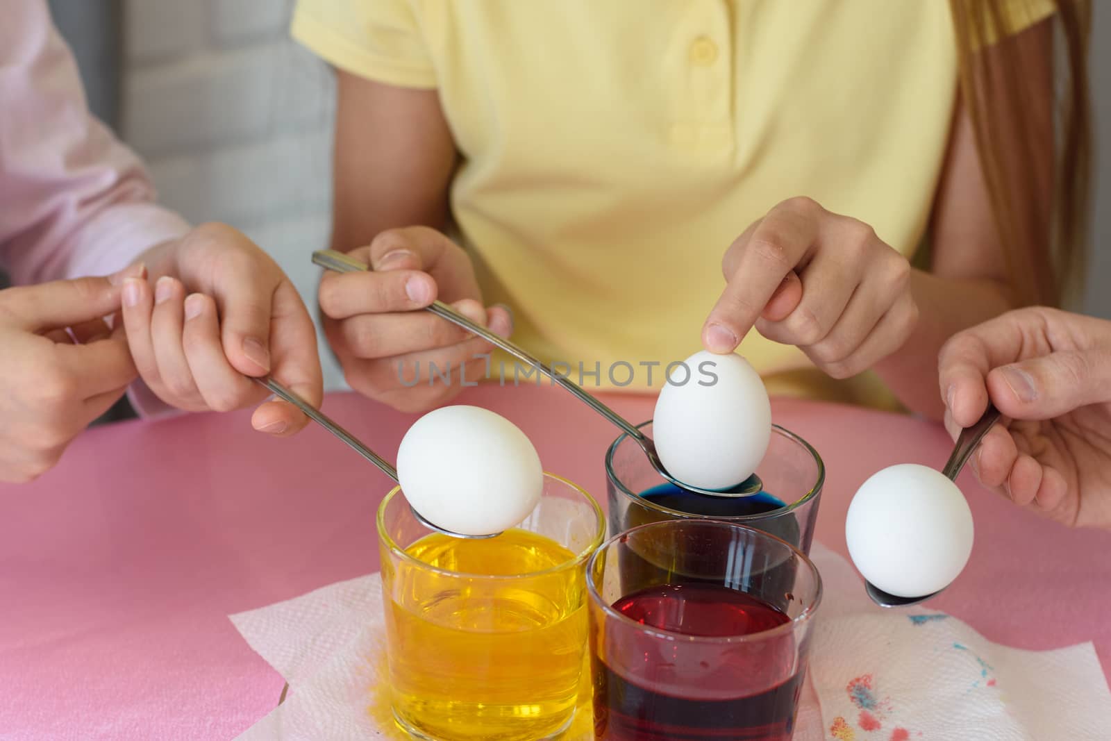 Hands dip chicken eggs in a dye solution