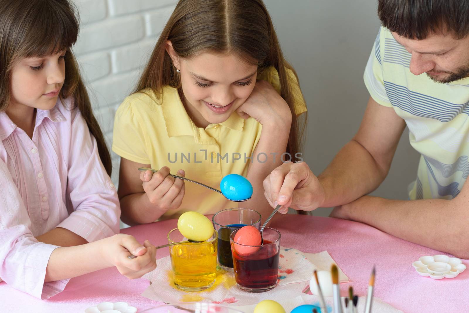 Daddy paint eggs in glasses with colorful dyes.