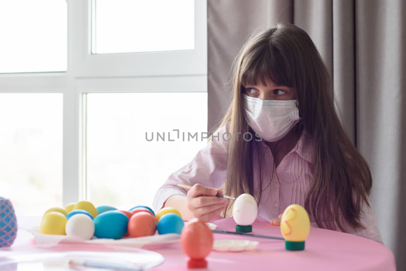 The sick girl alone paints Easter eggs for the holiday