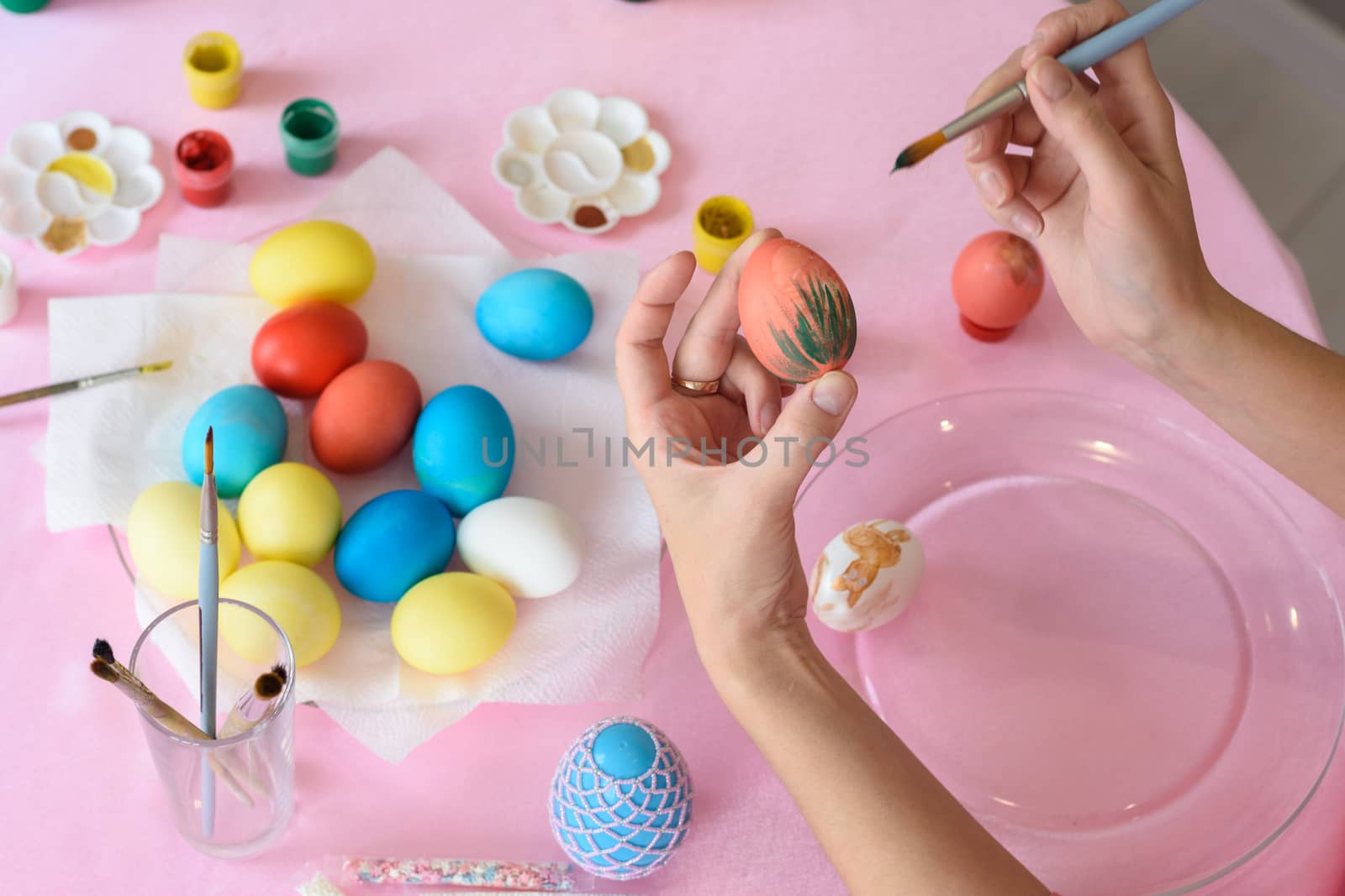 Female hand paints easter eggs, close-up