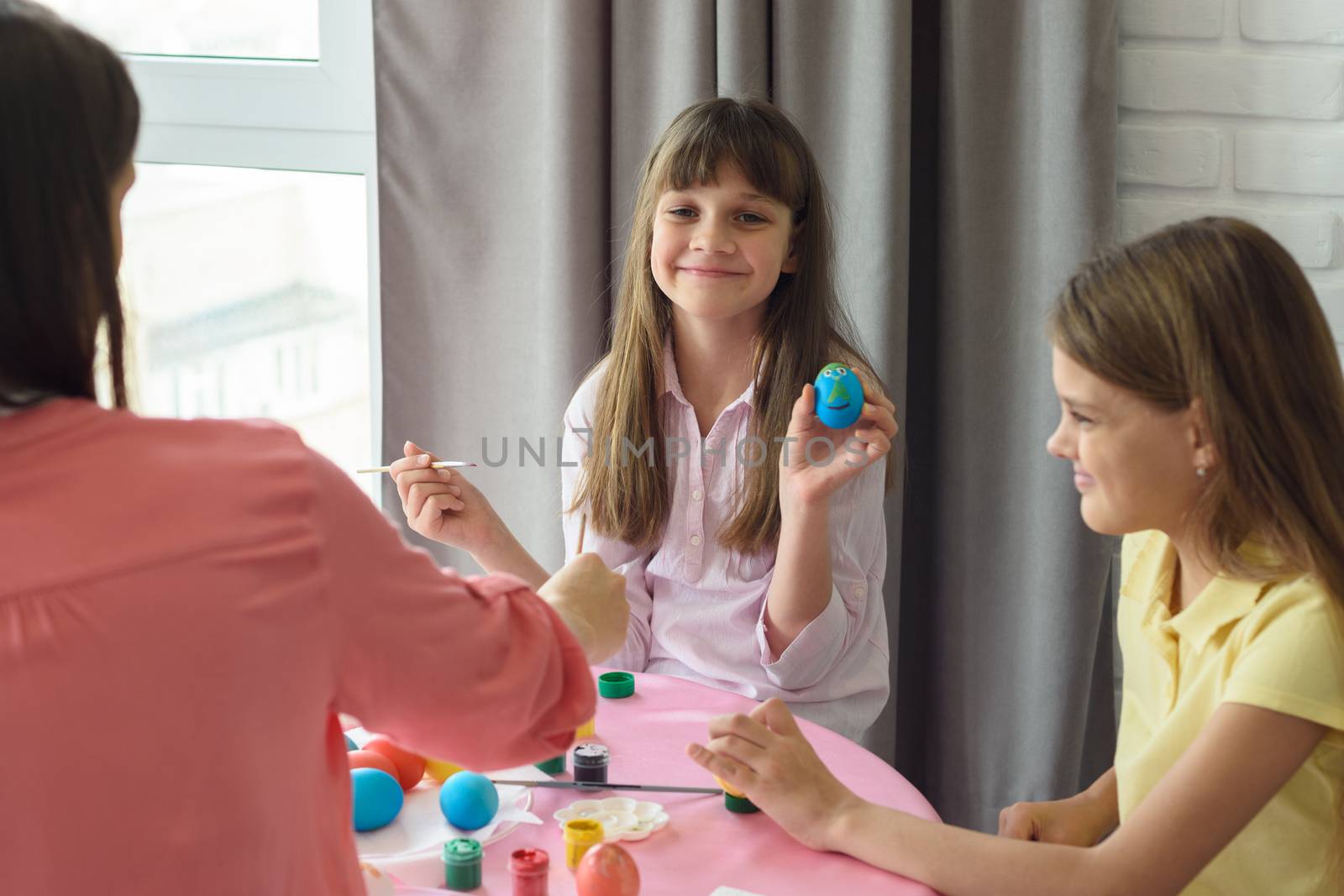 Happy girl shows a painted easter egg