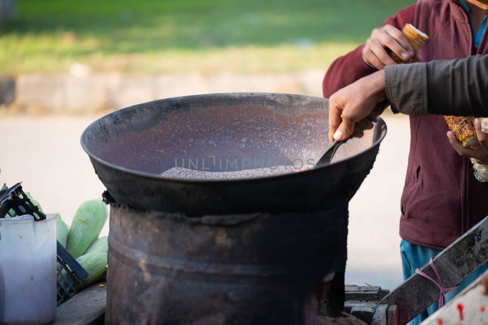 A Young boy is roasting fresh corn for the customers. by shaadjutt36