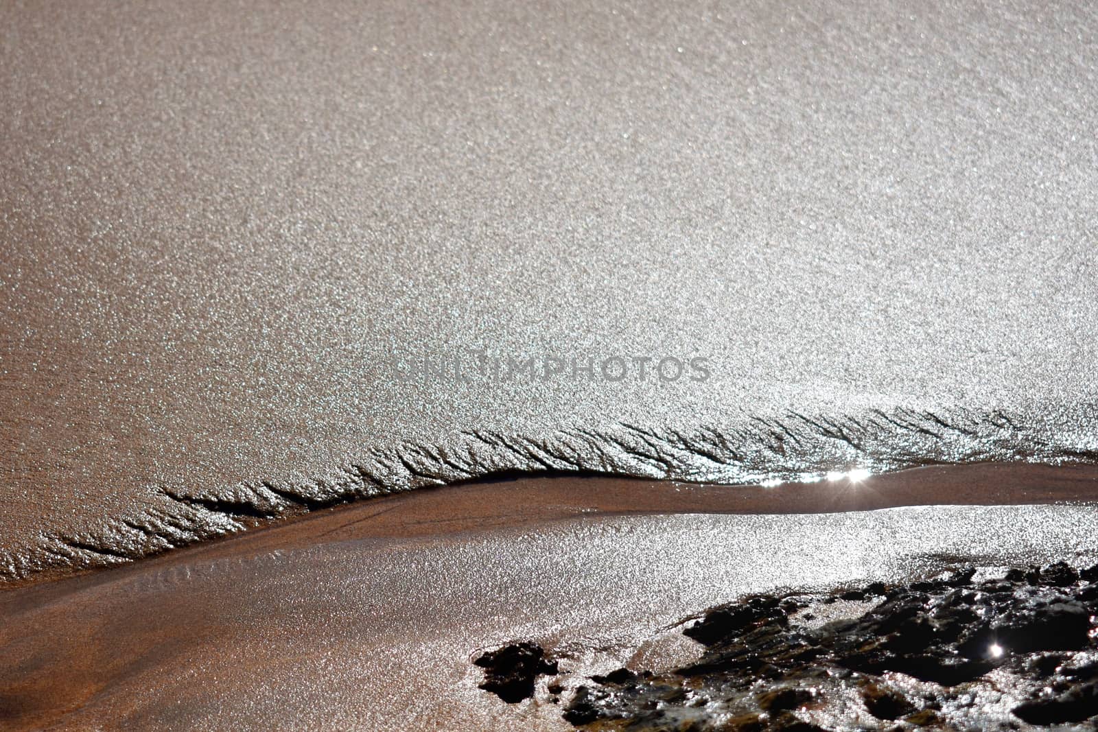 A close up of a stream near rocks at the beach.