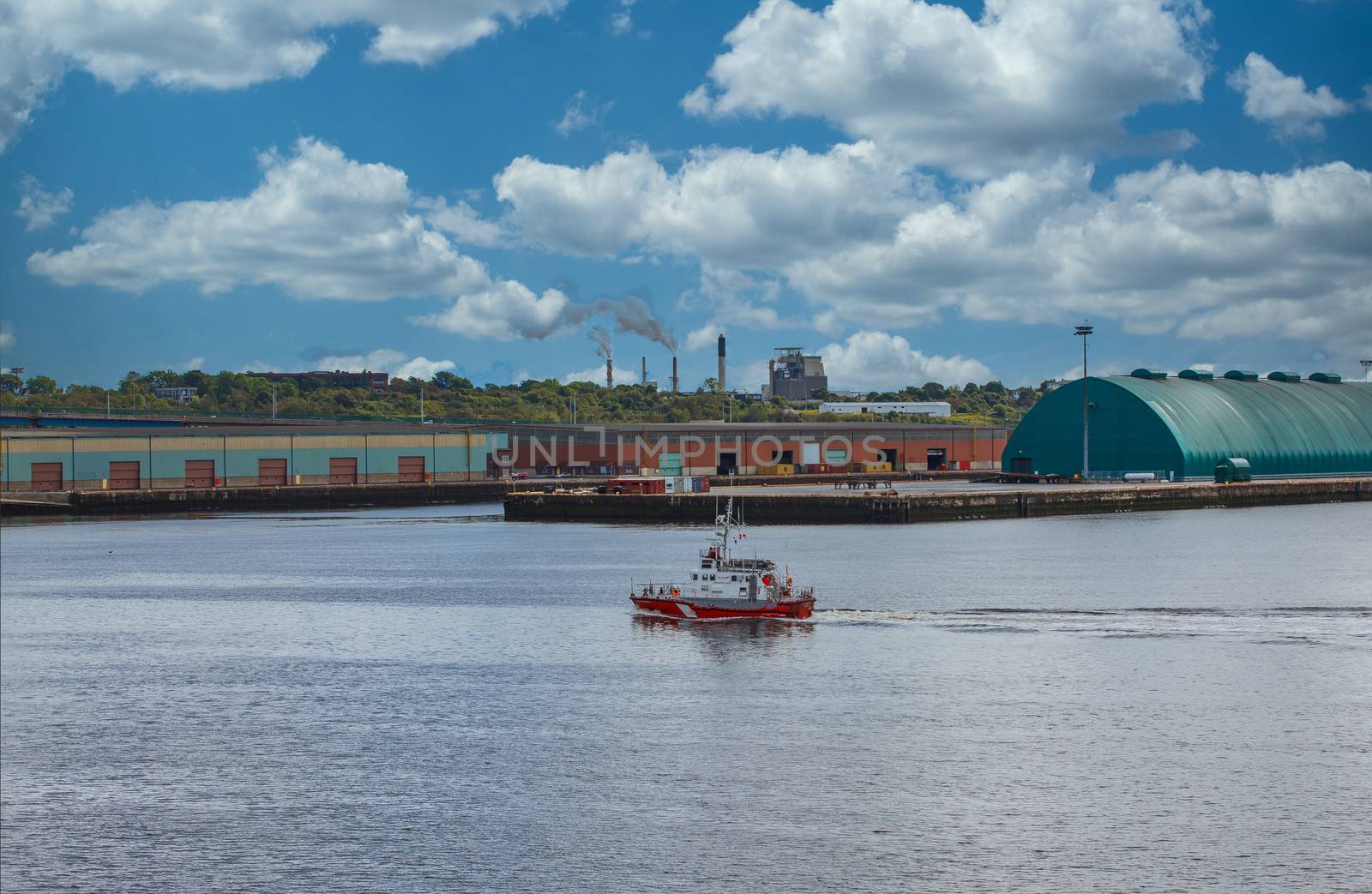 Canadian Coast Guard boat cruising past industrial area on coast of Canada