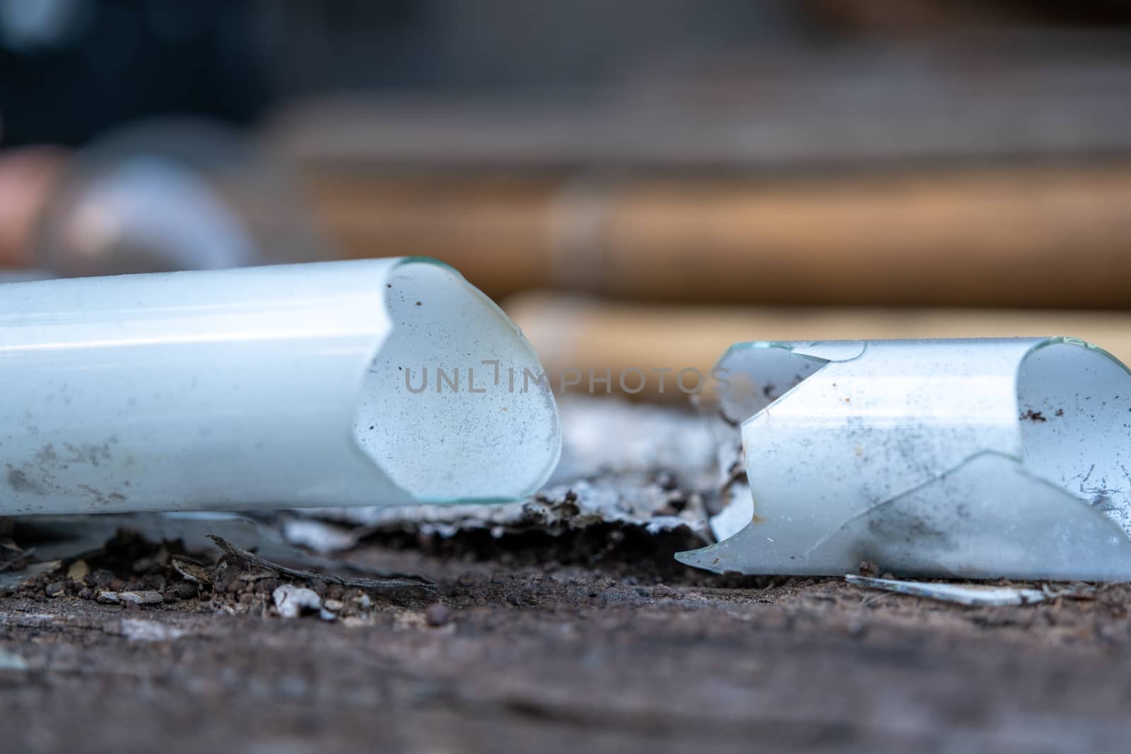 Shattered glass tube, broken energy saving bulb, compact fluorescent lamp tubular type with blur background by peerapixs