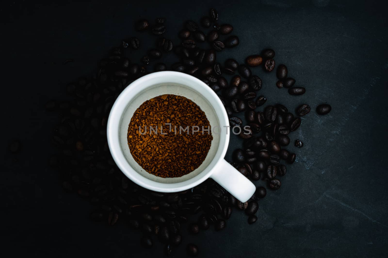 Top view of Instant coffee in cup on dark background with beans by peerapixs