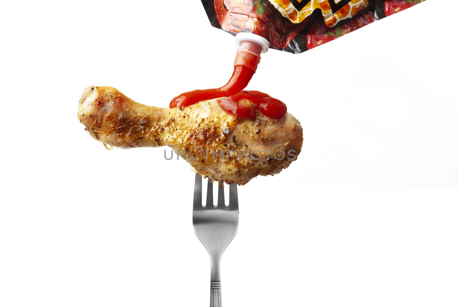 Chicken leg with ketchup on a fork isolated on white background