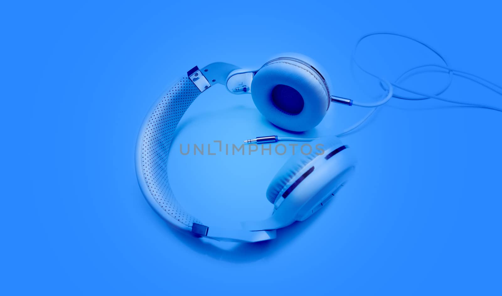 Top view blue headphones and Convention Aux cable 3.5 mm with copy space. Isolated on blue background