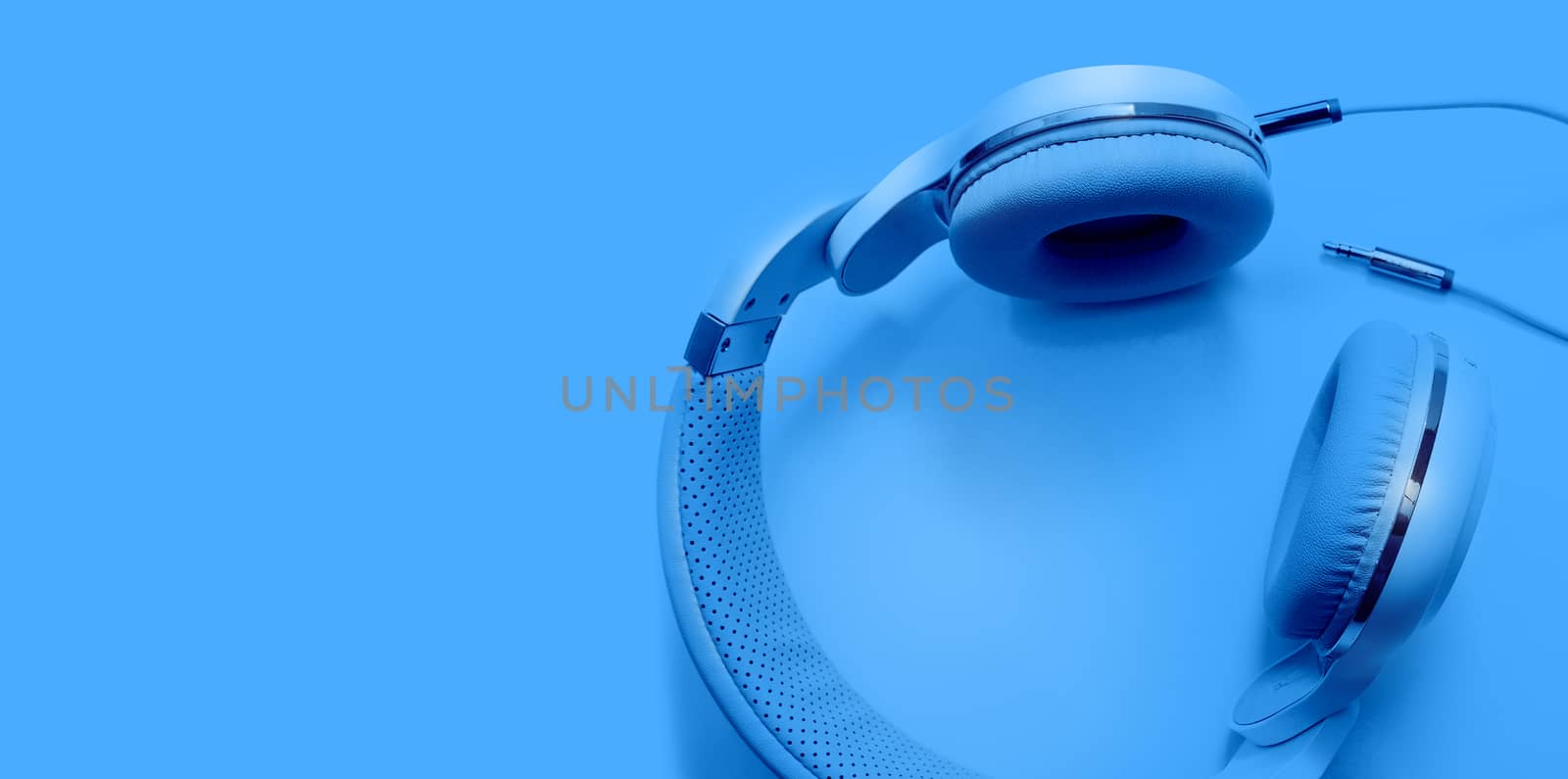 Top view blue headphones and Convention Aux cable 3.5 mm. Isolated on blue background