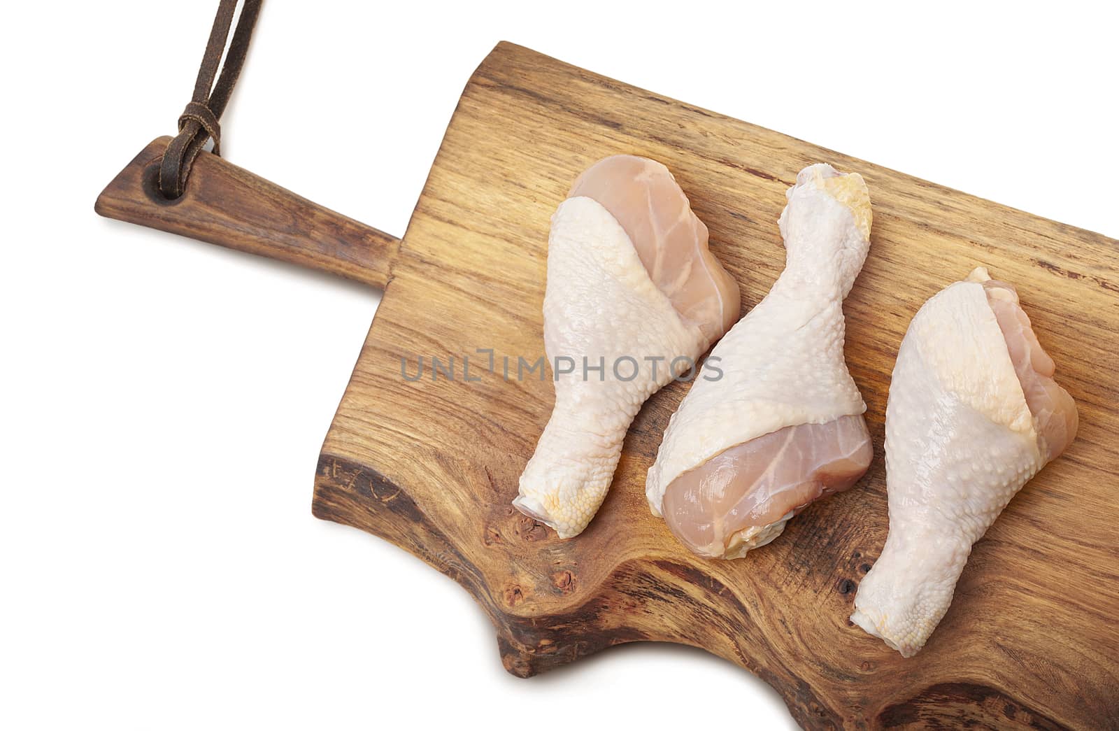 Raw uncooked chicken legs, drumsticks on wooden board. Isolated on white background