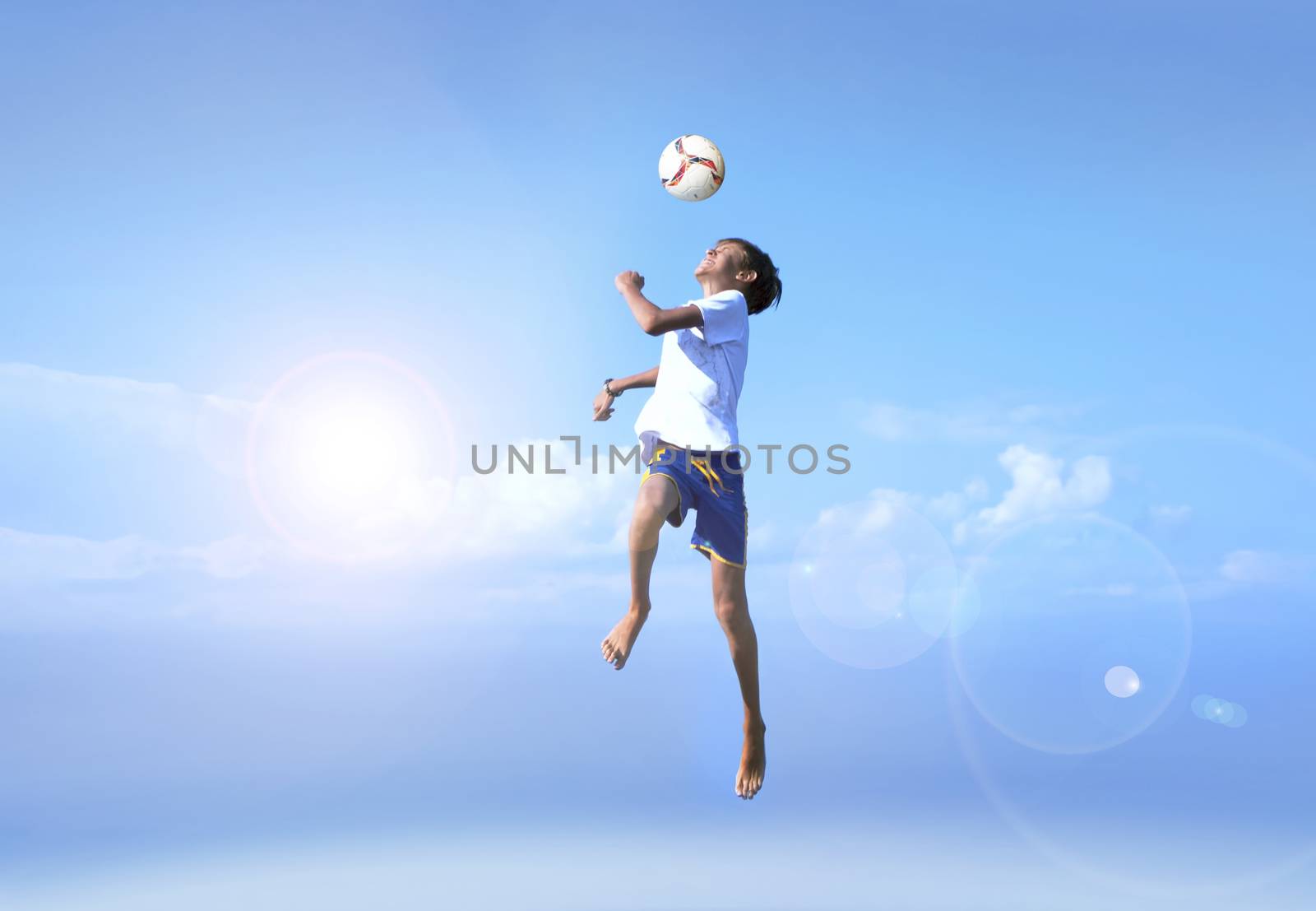 MOTION BLUR SHOT. A young boy in a jump, football player doing amazing makes a headbutt a background of blue sky. Happy, joy, good mood