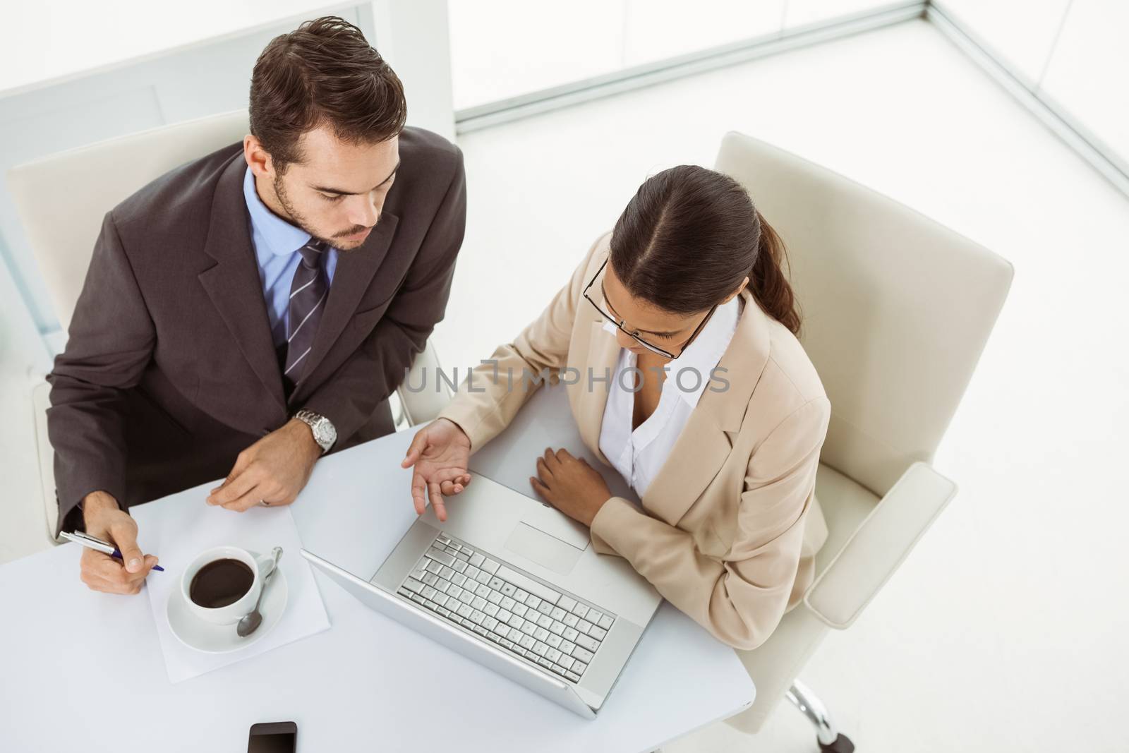 Two young business people using laptop in office