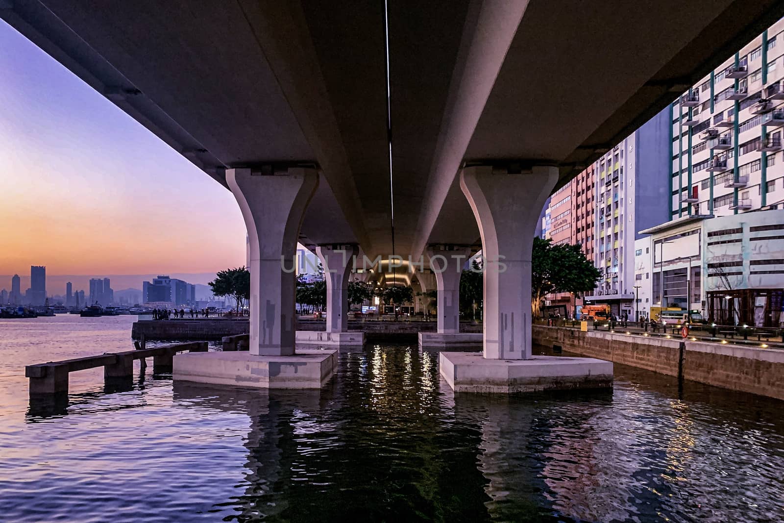 The outdoor park underneath car bridge near the Hong Kong river in downtown district at sunset
