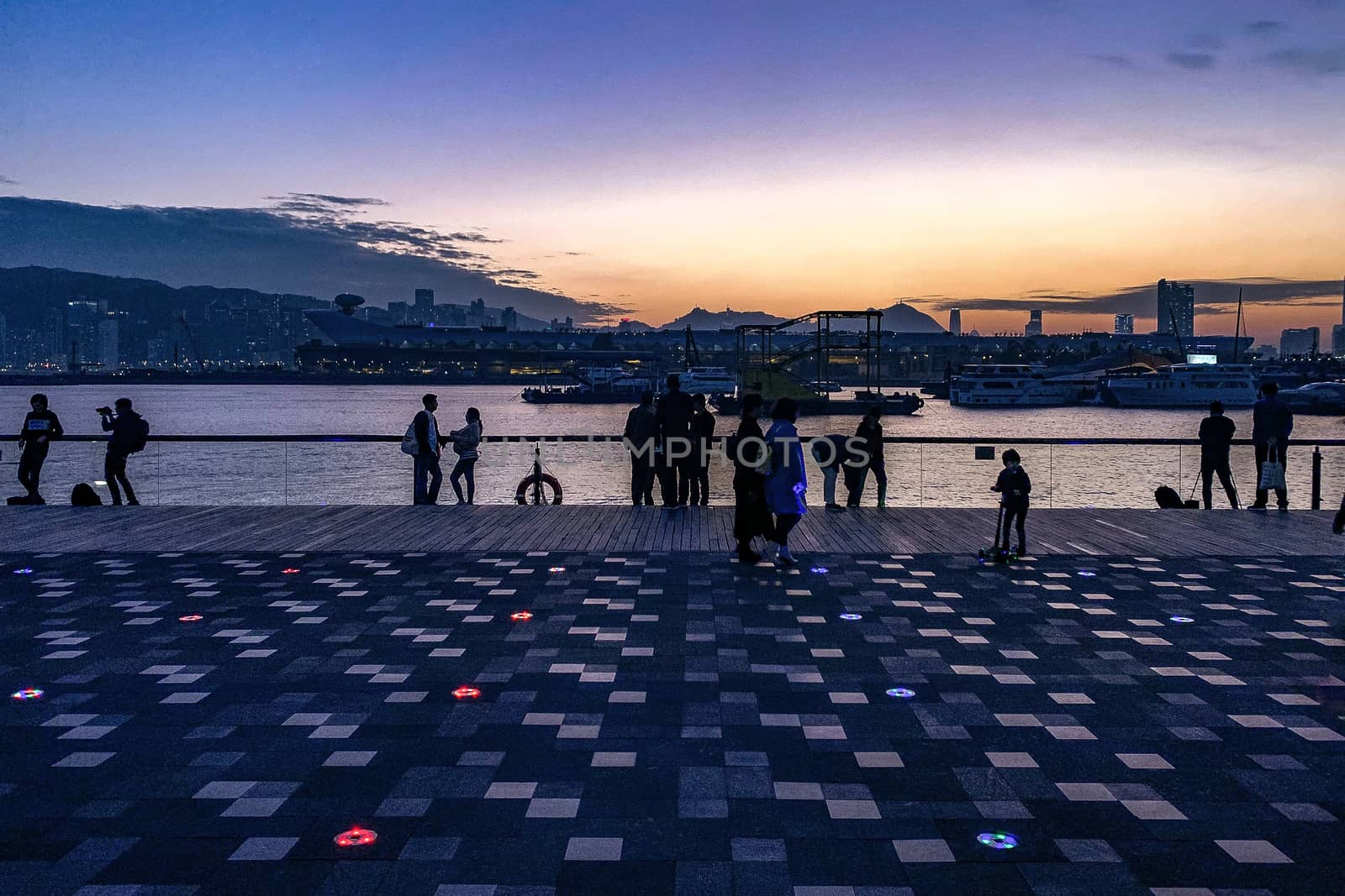 The silhouette of people near the Hong Kong river in downtown district at sunset