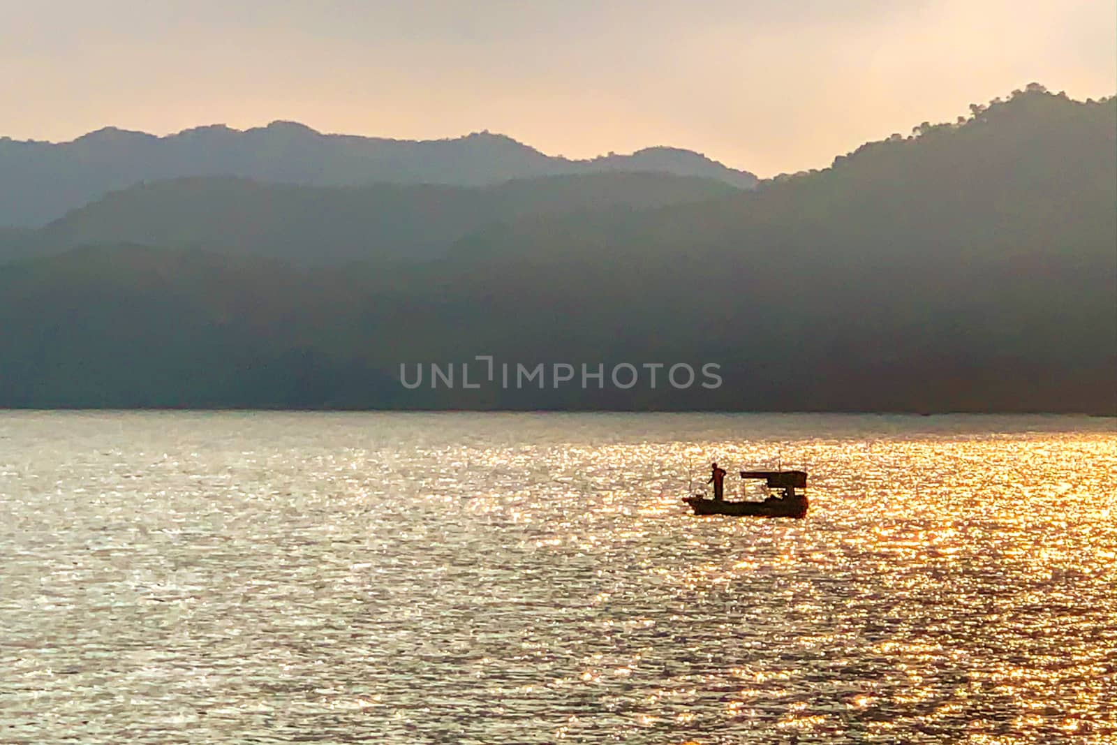 The silhouette of wood fishing boat on the sea with mountain 
