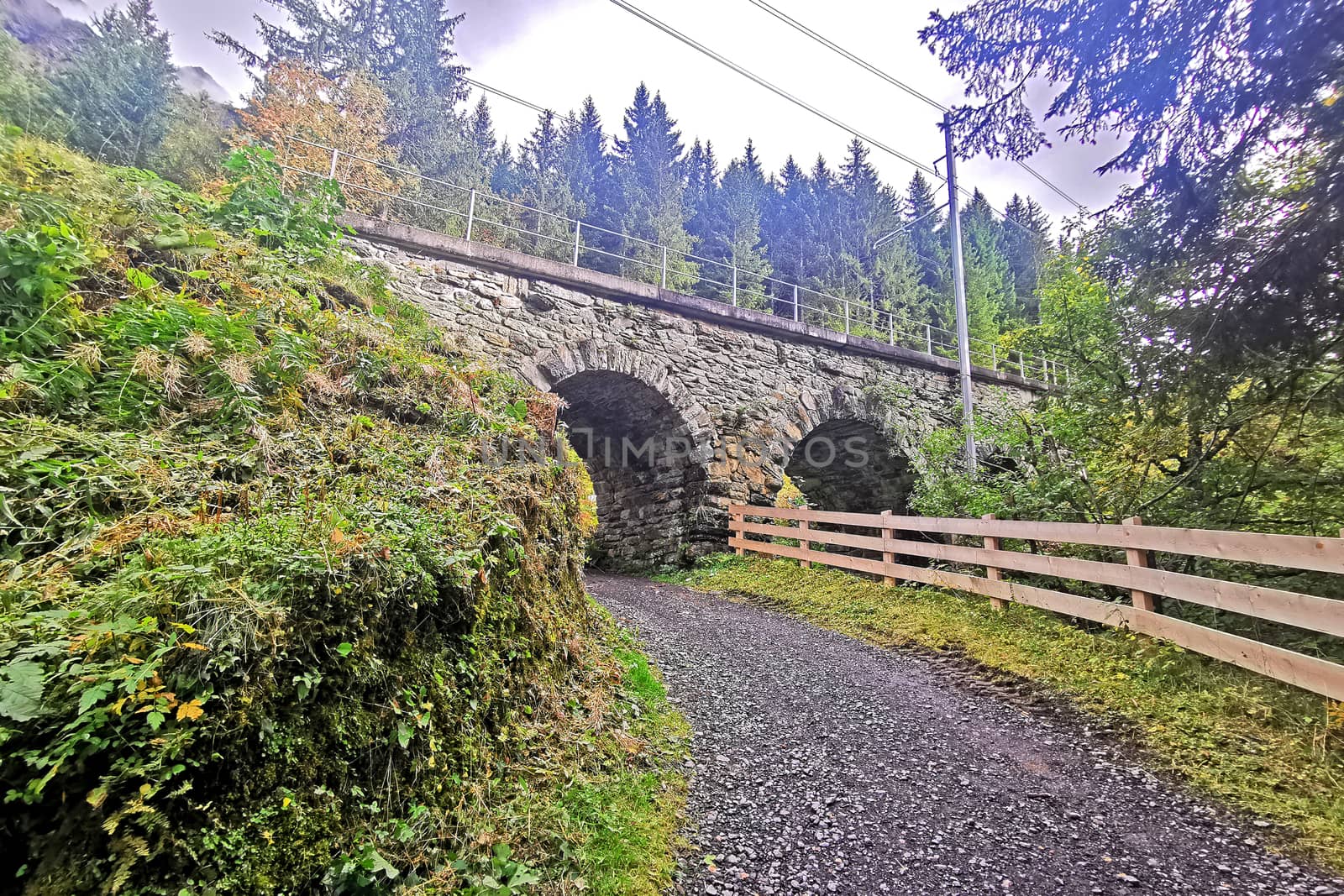 Stone bridge, road, wooden fence in Switzerland Grindelawld moun by cougarsan