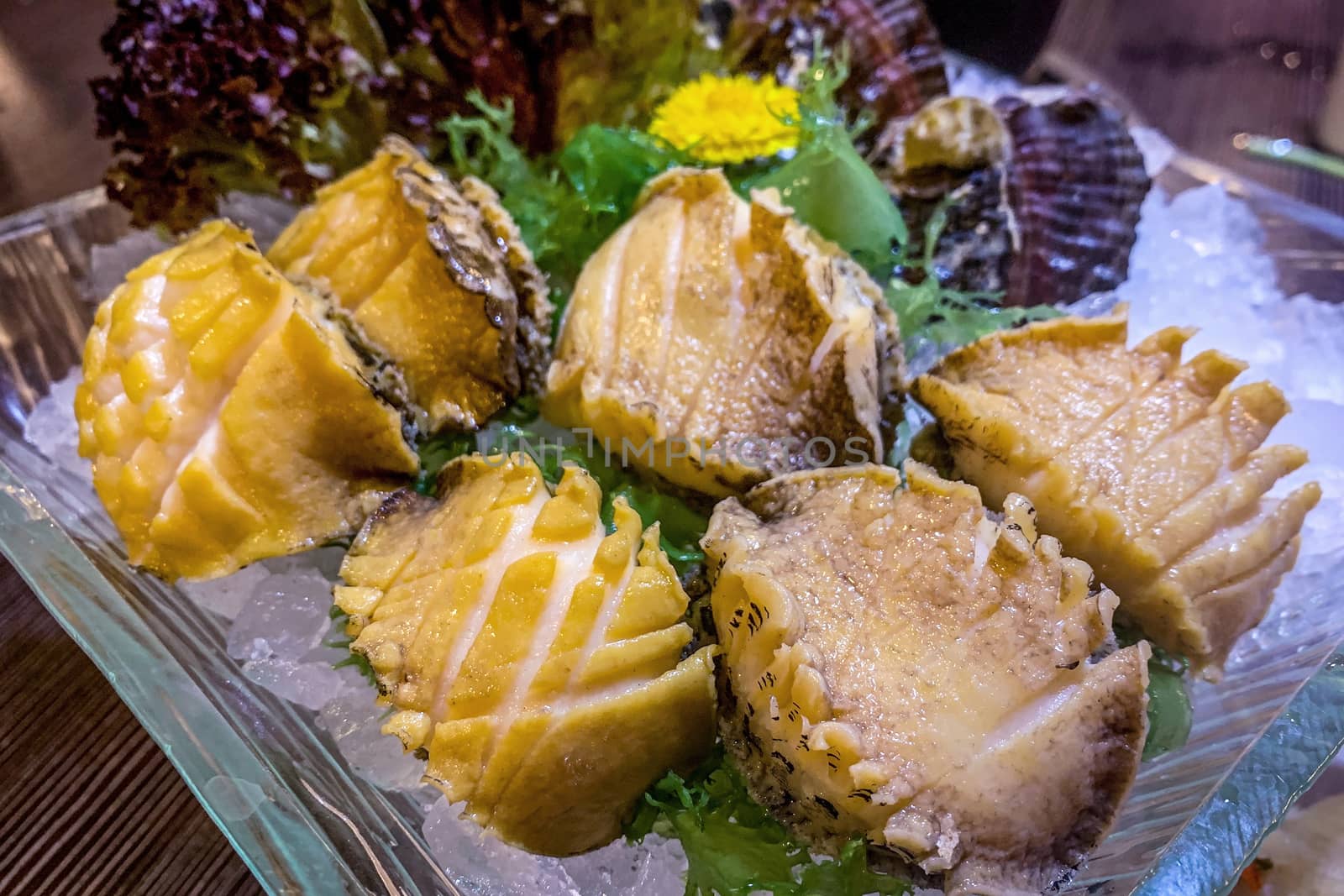 raw seafood abalone on glass plate and ice in restaurant table
 by cougarsan