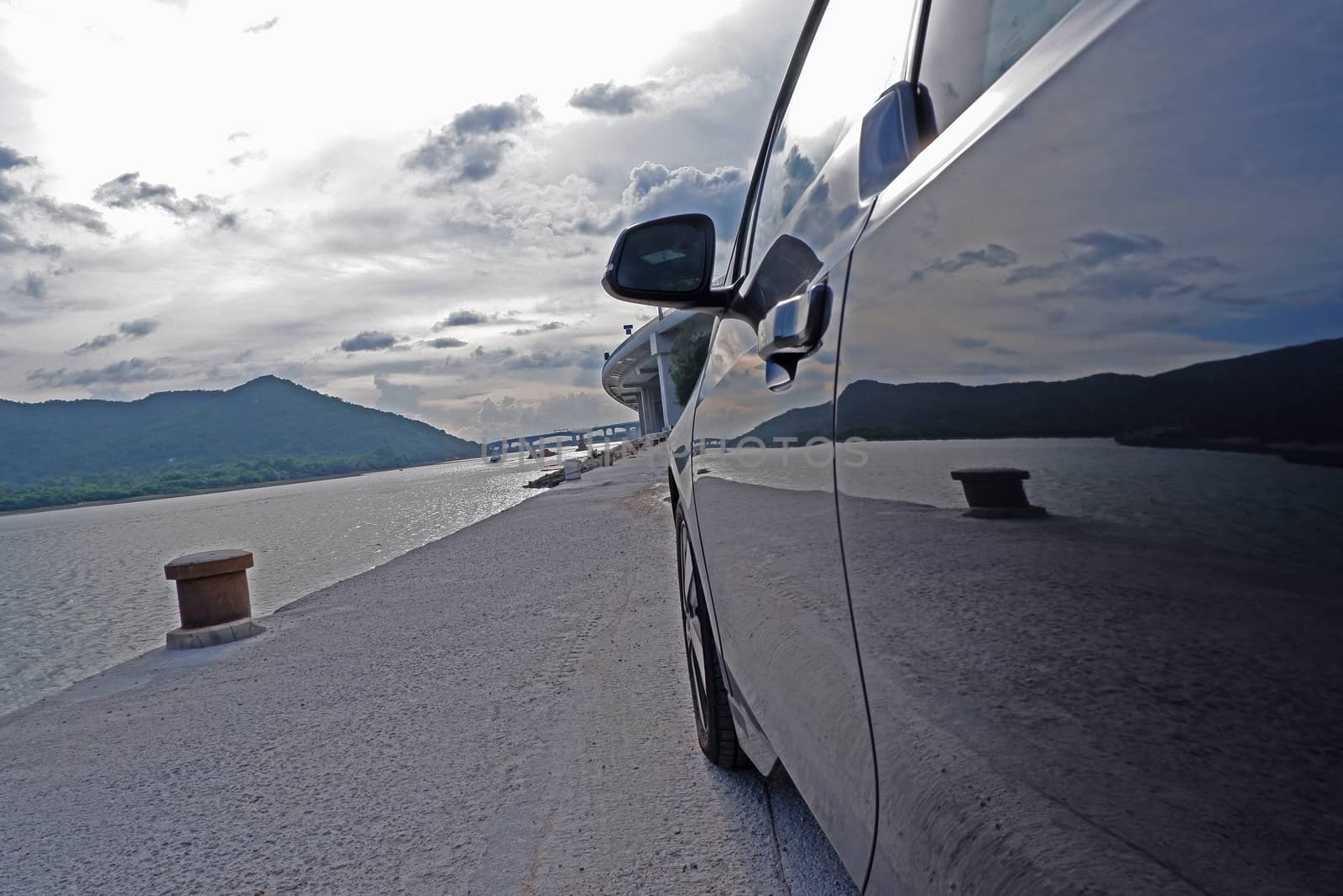 The close up of car door and mirror, pier, ocean, sky and mountain