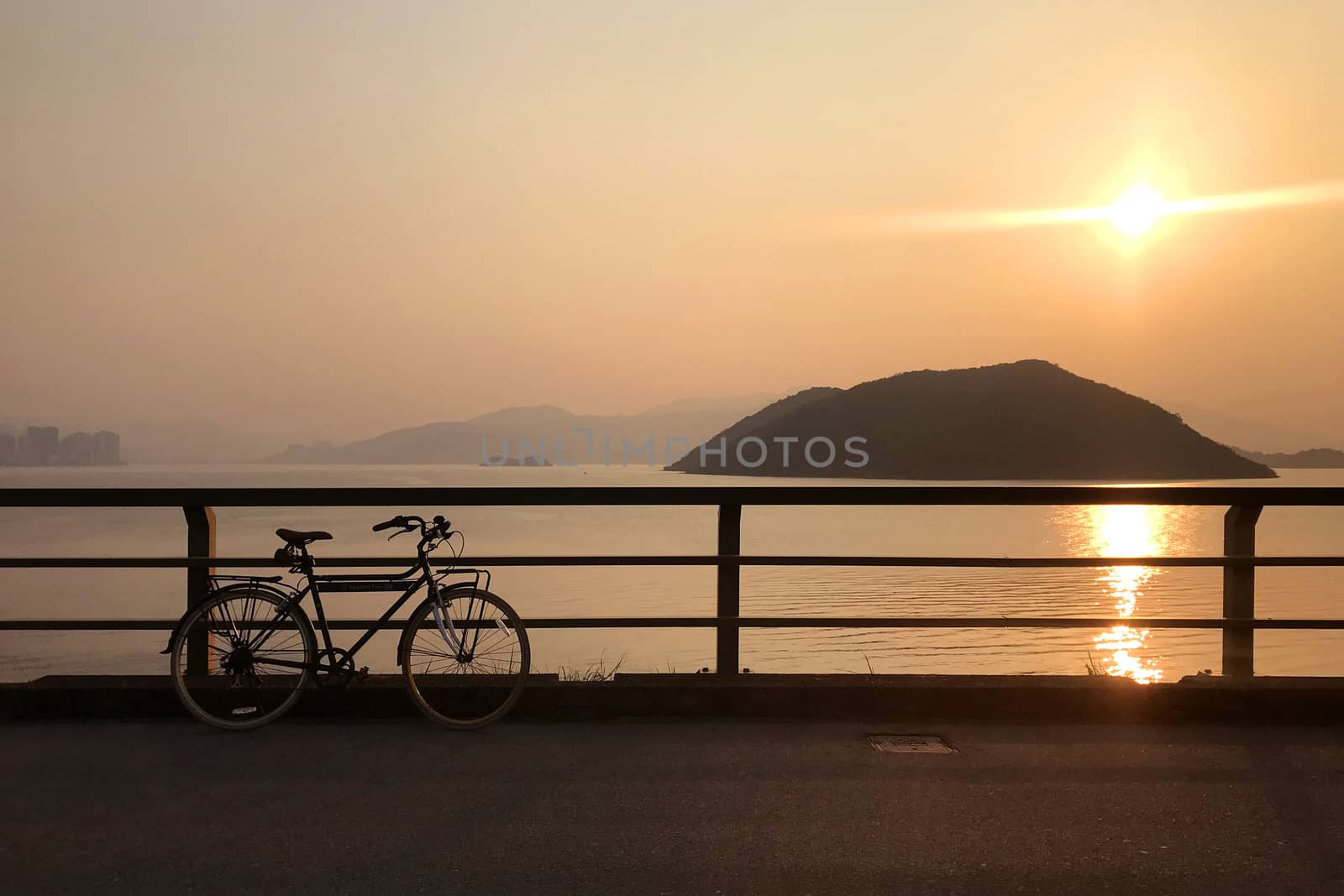 Silhouette of retro bicycle, fence, ocean, mountain at sunset by cougarsan