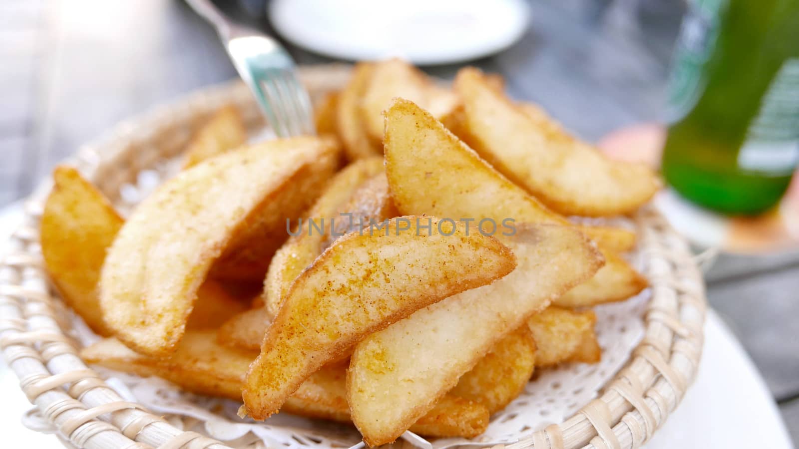 french fries on the basket plate and bottle of beer