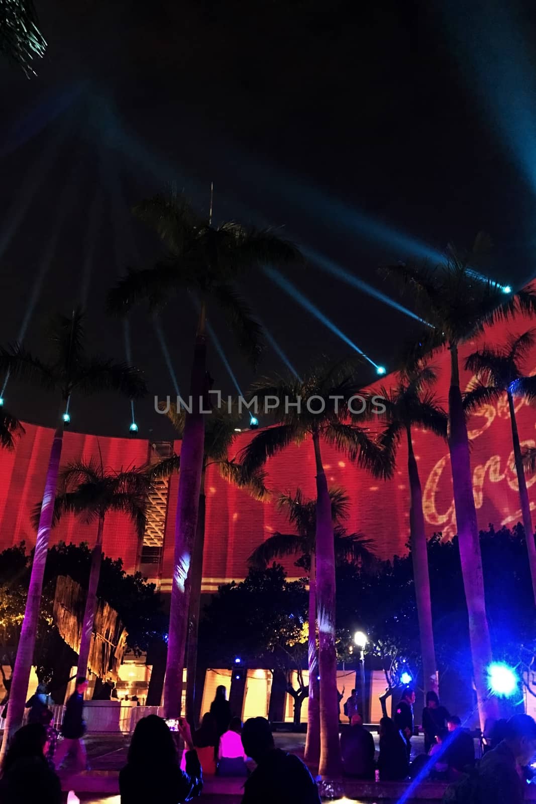 Colorful laser show performance around the architectural building in the city at night time