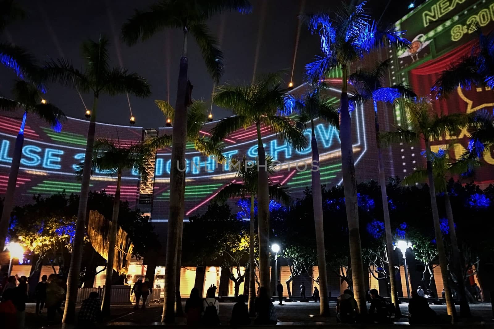 Colorful laser show performance around the architectural building in the city at night time