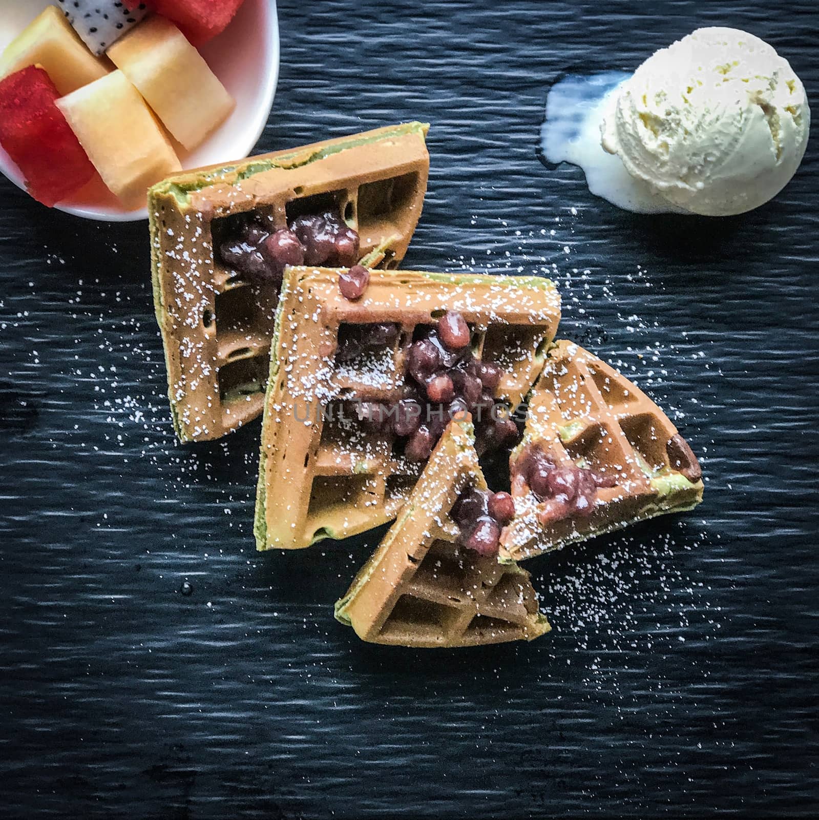 Waffle with red beam, ice cream, fruit on the textured dish