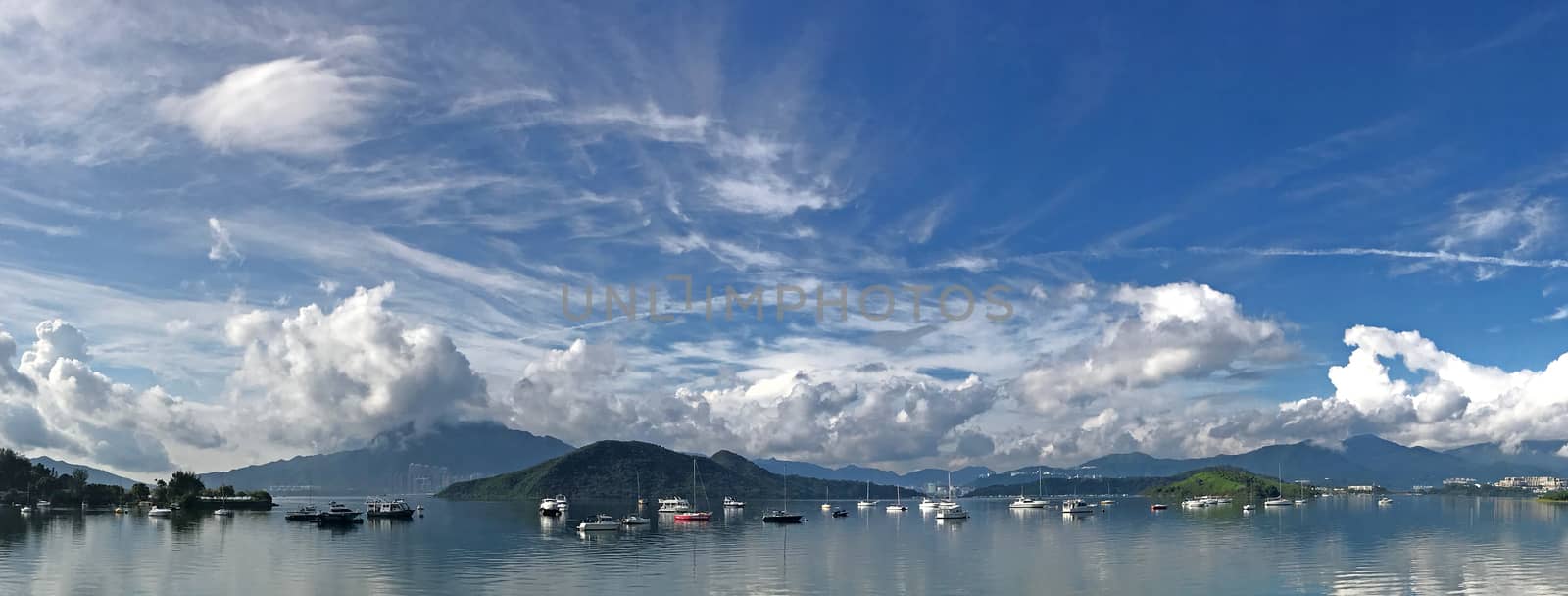Panorama beautiful photography of mountain, cloudscape, boats, sailboat and yacht on lake with clean reflection