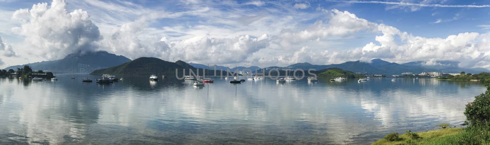 Panorama beautiful photography of mountain, cloudscape, boats, sailboat and yacht on lake with clean reflection